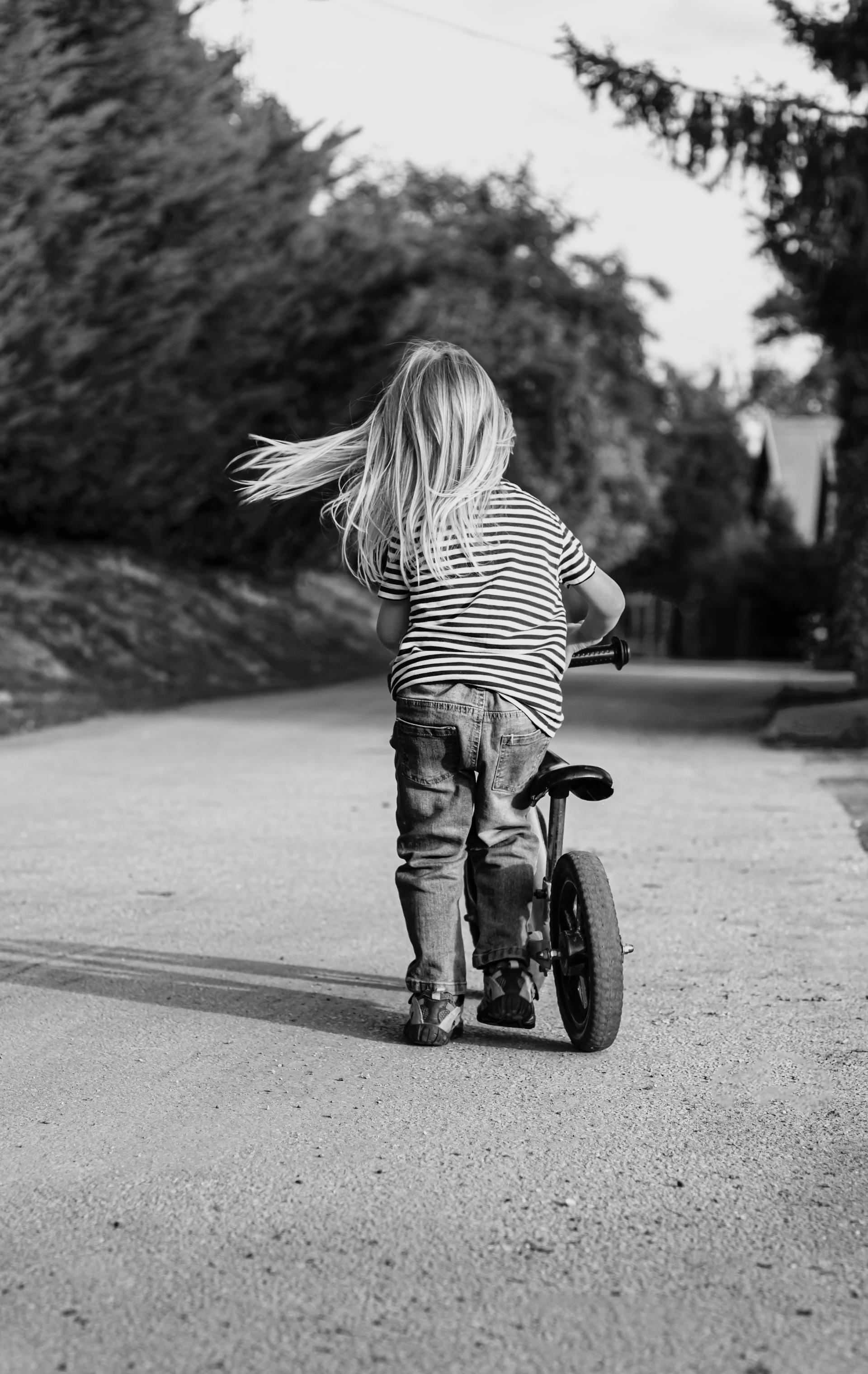 Scatto in scala di grigi di una bambina che va in bicicletta | Fonte: Pexels