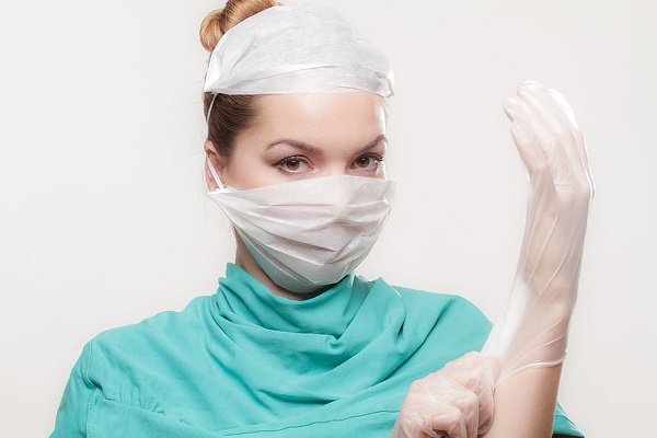 Médica colocándose guantes de látex. | Foto: Pxfuel