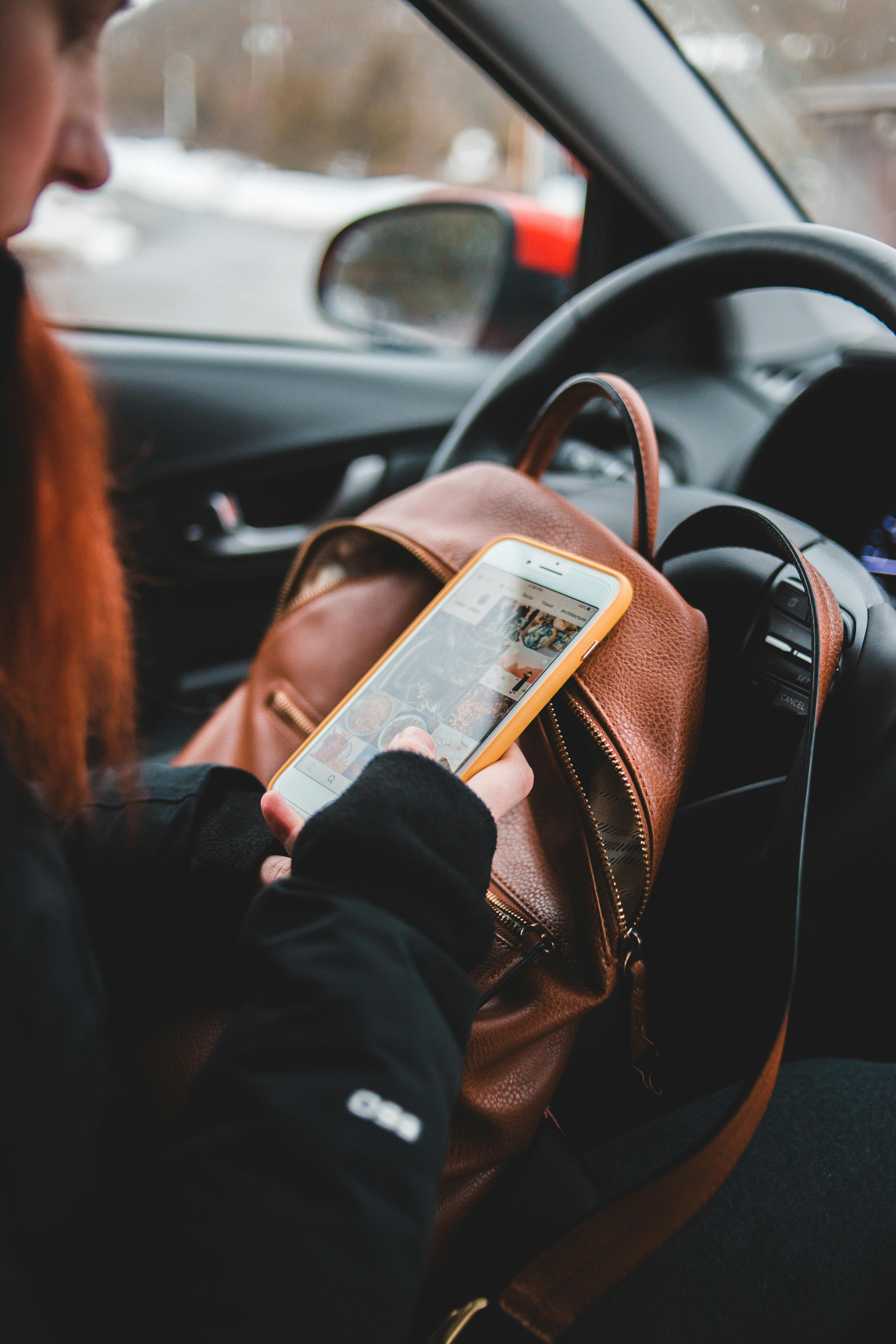 Una mujer consulta su teléfono desde el interior del Automóvil | Fuente: Pexels