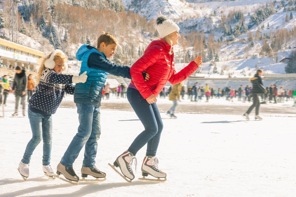 Mujer patinando sobre el hielo con dos niños detrás. | Foto: Shutterstock