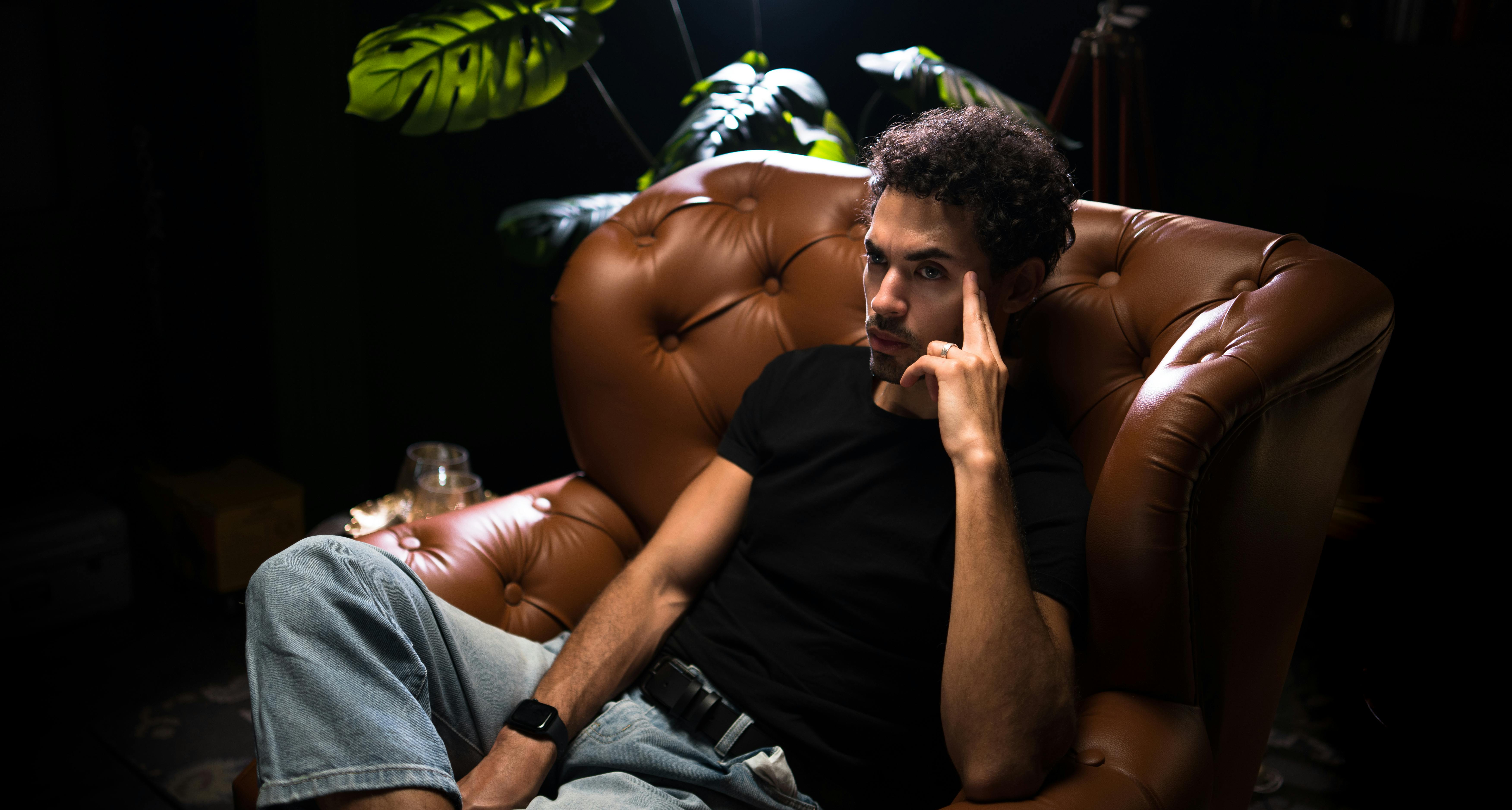 Un hombre serio sentado en una silla de cuero | Fuente: Pexels
