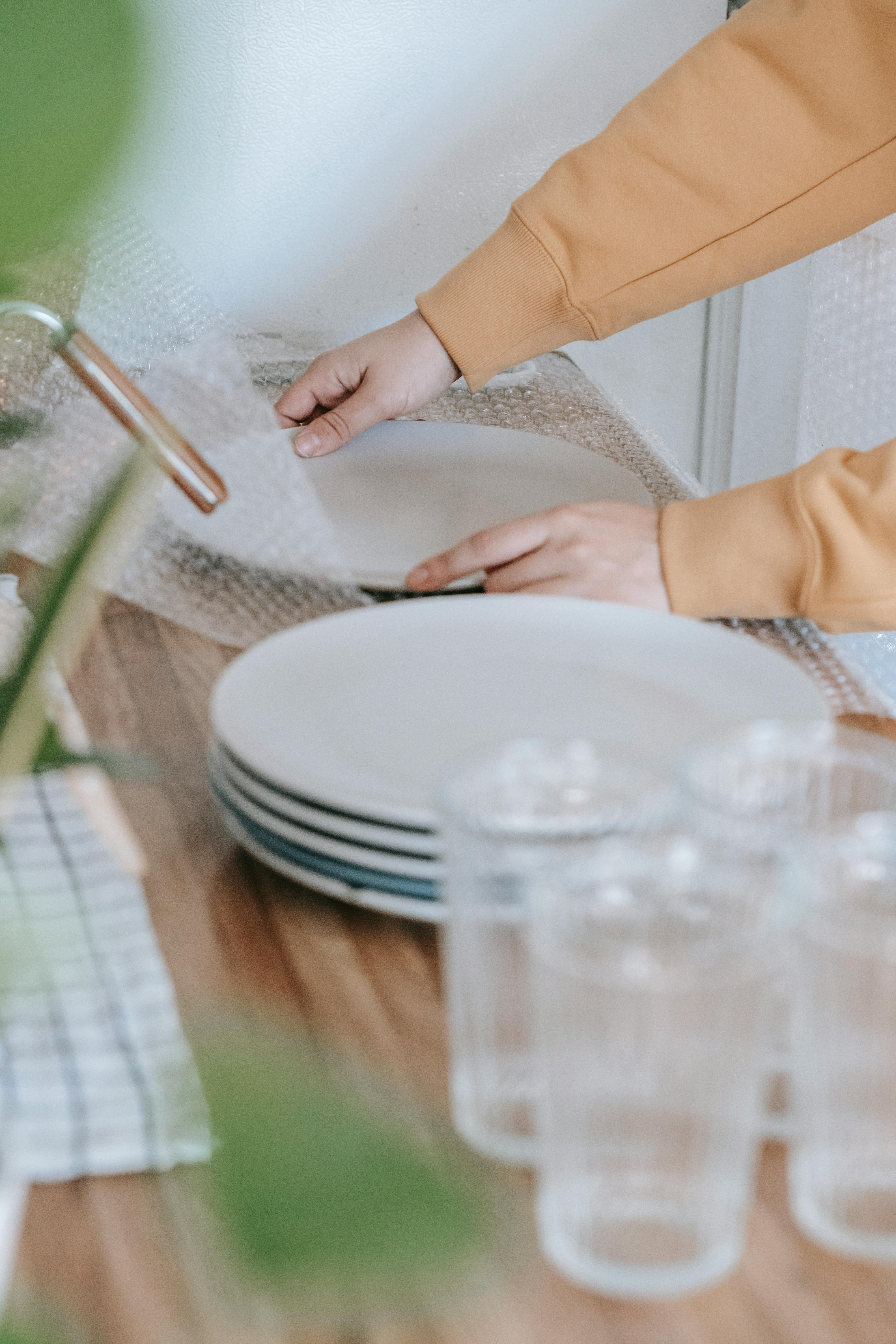 Una mujer poniendo plástico de burbujas en platos | Fuente: Pexels