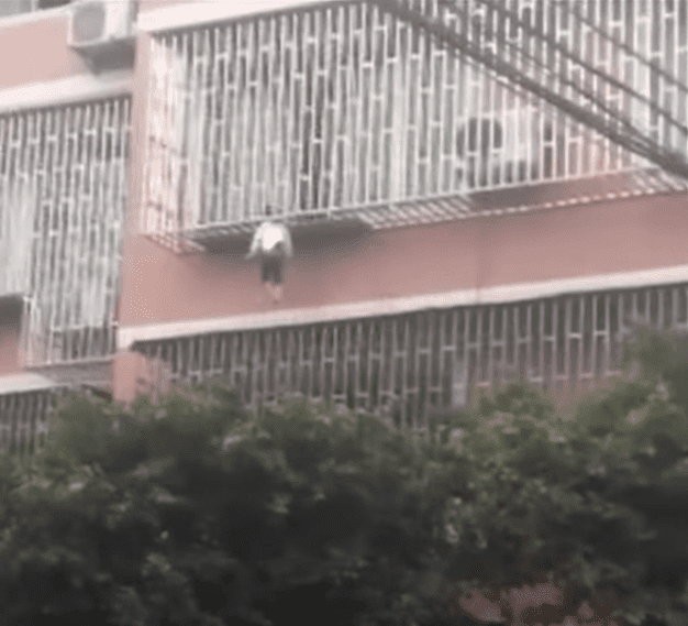 Niña colgando del cuello en un balcón. | Fuente: Youtube/CGTN