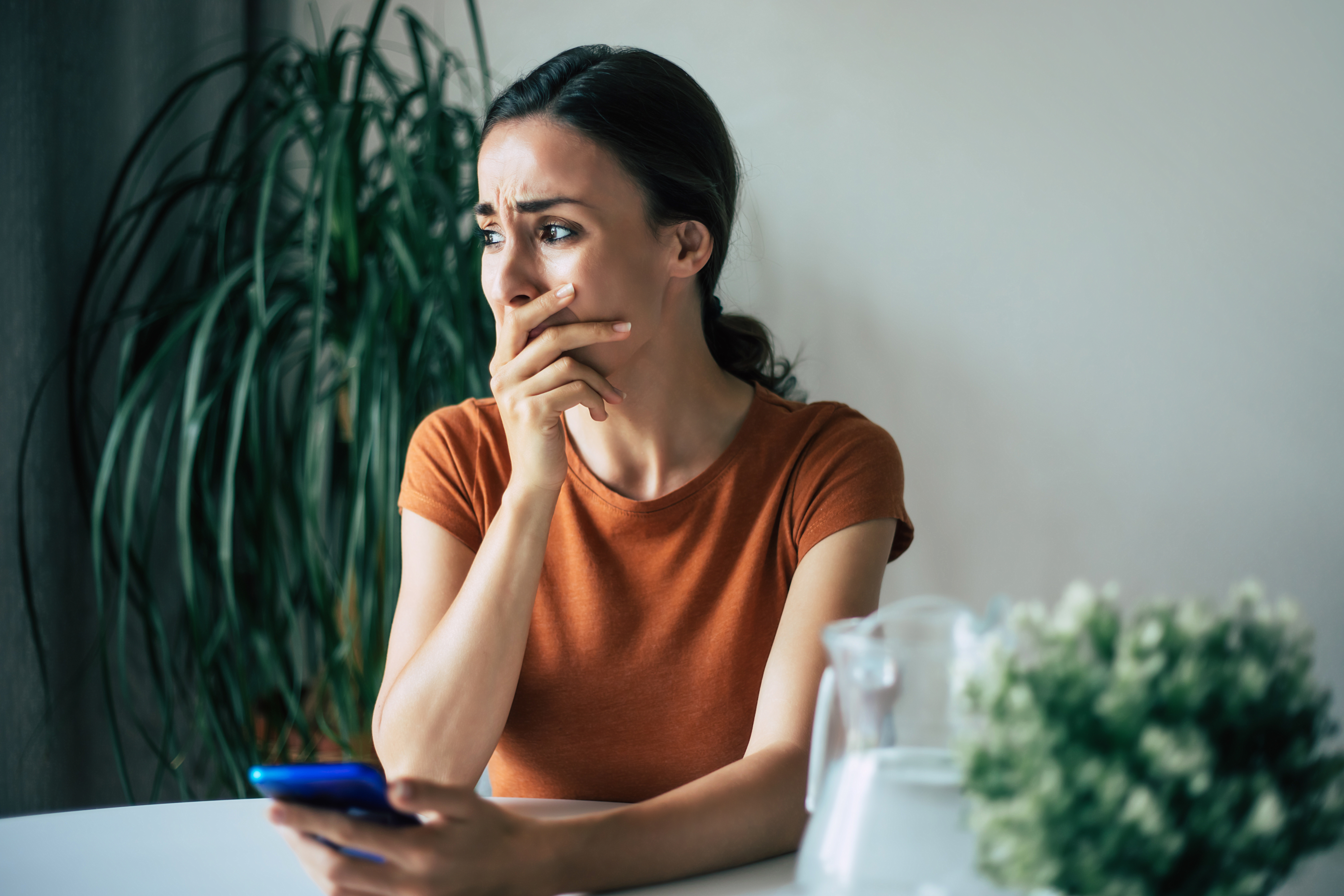 Una joven entre lágrimas sostiene un móvil | Fuente: Shutterstock