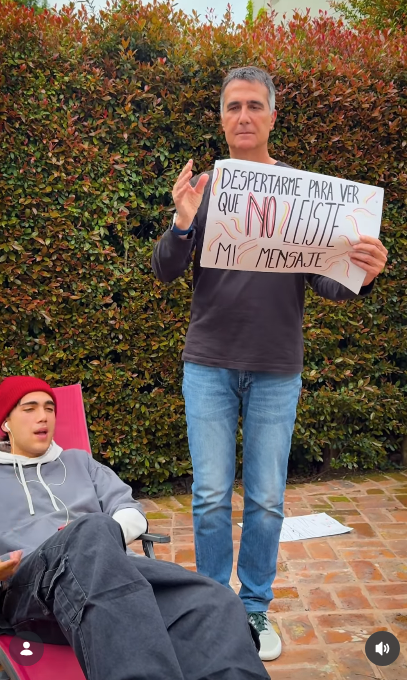 Antonio Laje acompañó la letra de la canción mostrando la cartulina con el texto "DESPERTARME PARA VER QUE NO LEÍSTE MI MENSAJE" mientras hacía un gesto explicativo con su mano derecha. A su lado, Ezequiel (Leish) entonaba las estrofas de "Placer Culposo" recostado al aire libre. | Fuente: Instagram/leish.ar