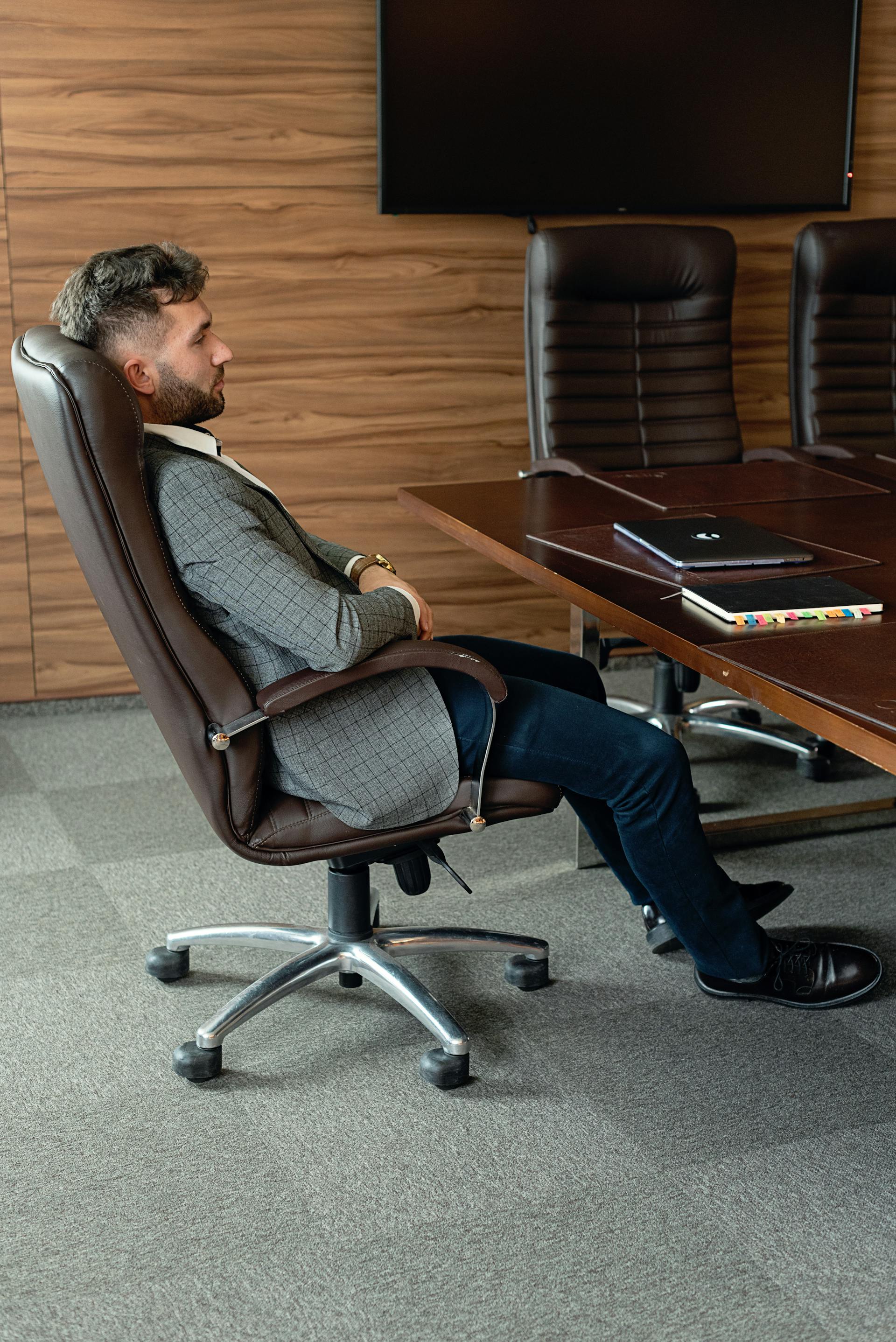 Vista lateral de un hombre recostado en su silla de oficina | Fuente: Pexels