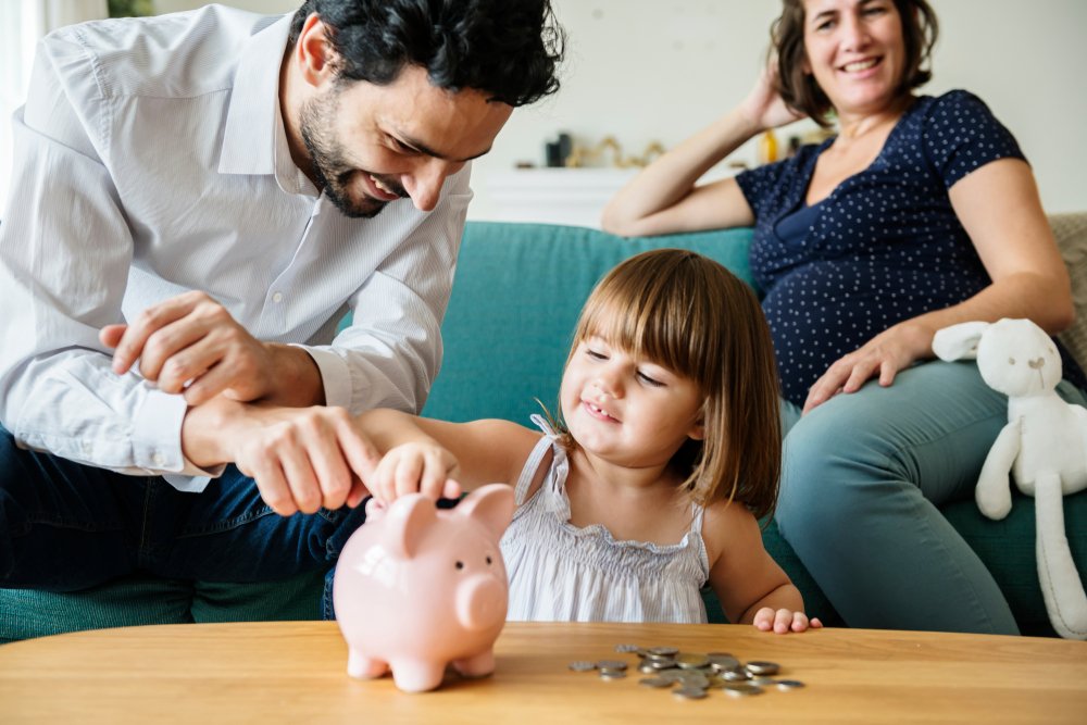 Padres enseñándole a su hija a ahorrar dinero. | Foto: Shutterstock