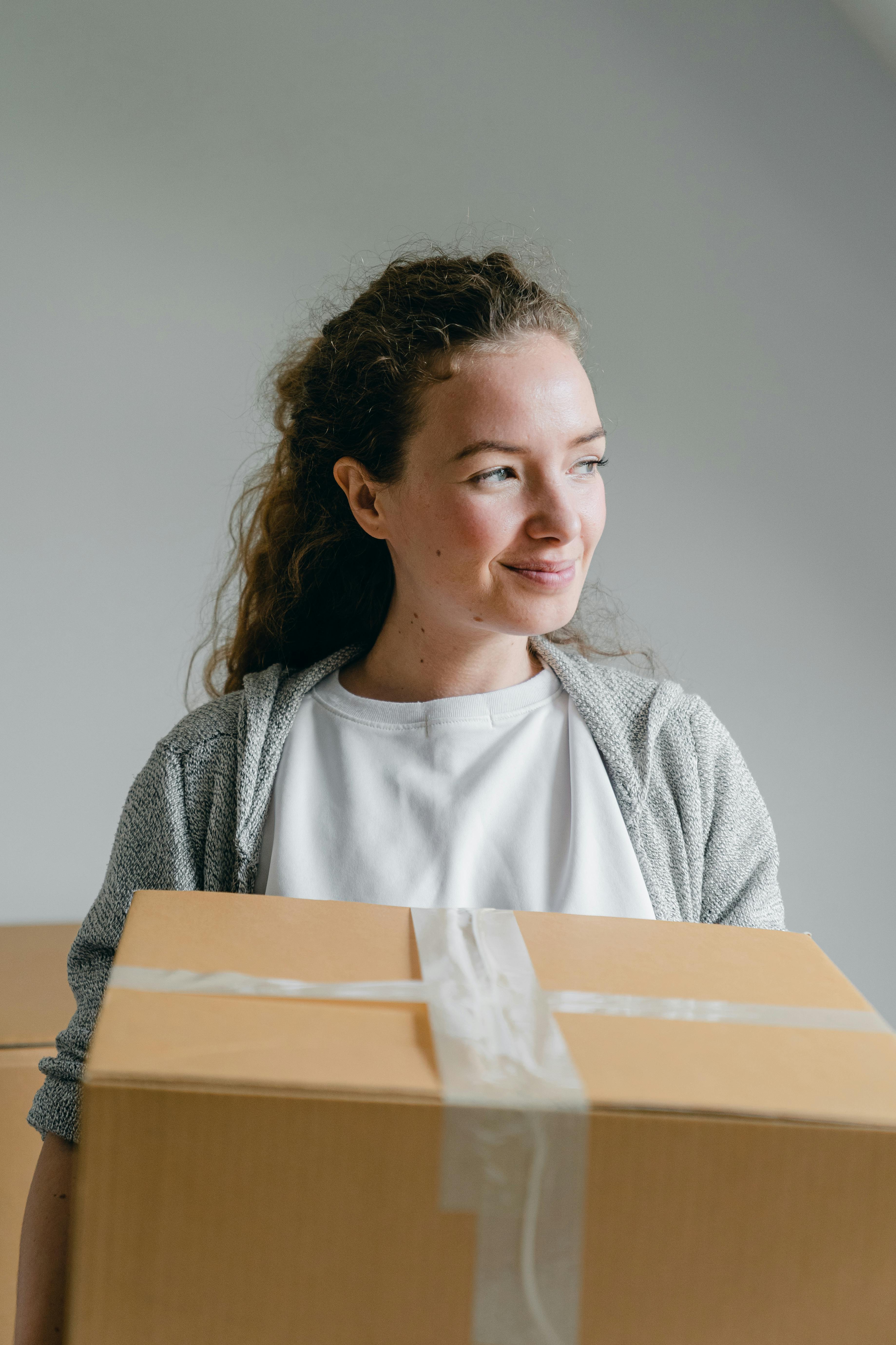 Una mujer sonriente sujetando una caja encintada | Fuente: Pexels