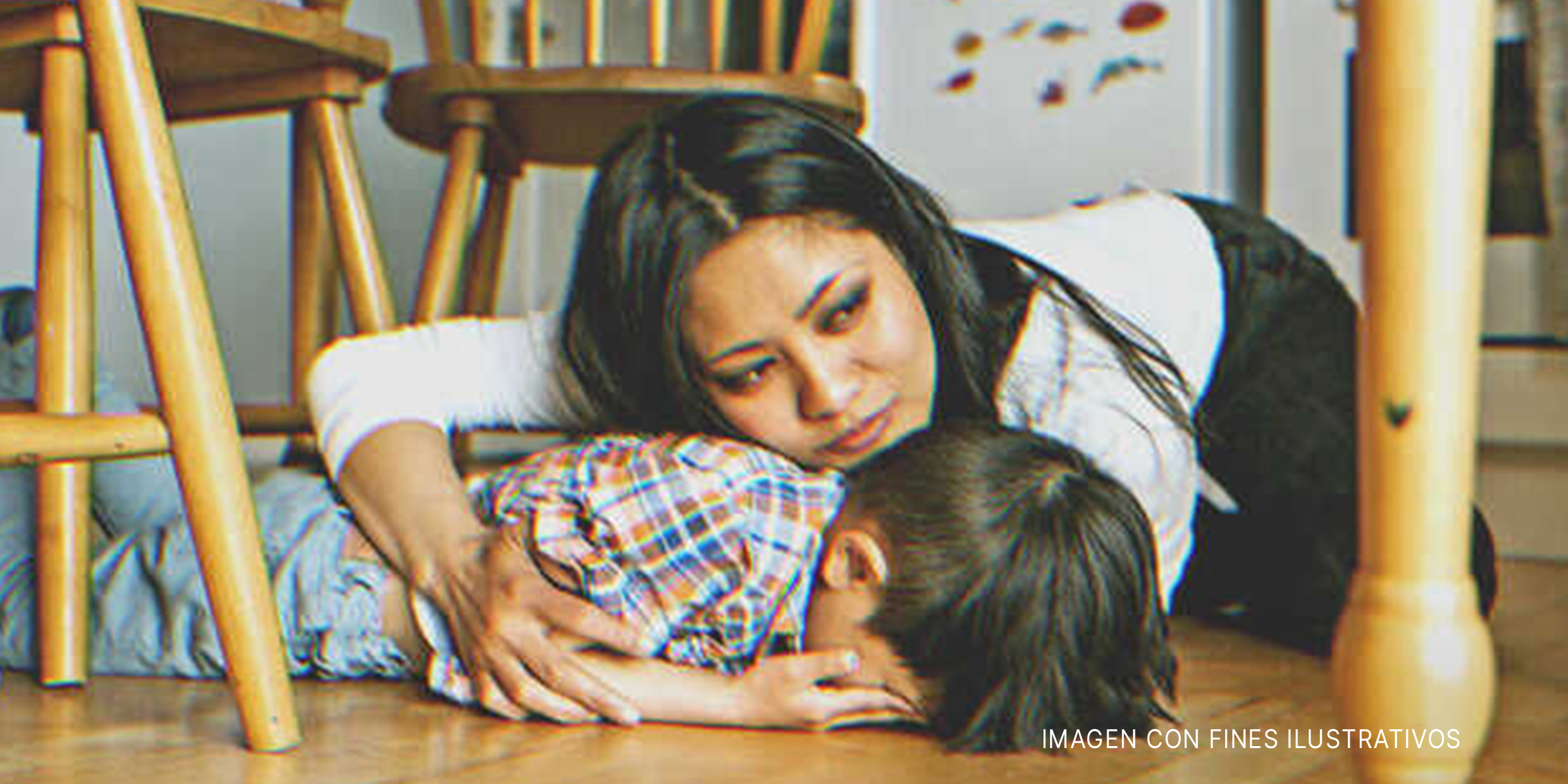 Mujer sujetando a un niño bajo la mesa. | Fuente: Getty Images