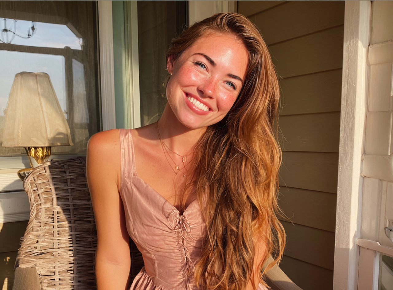 Una joven sonriente con un vestido rosa | Fuente: Midjourney