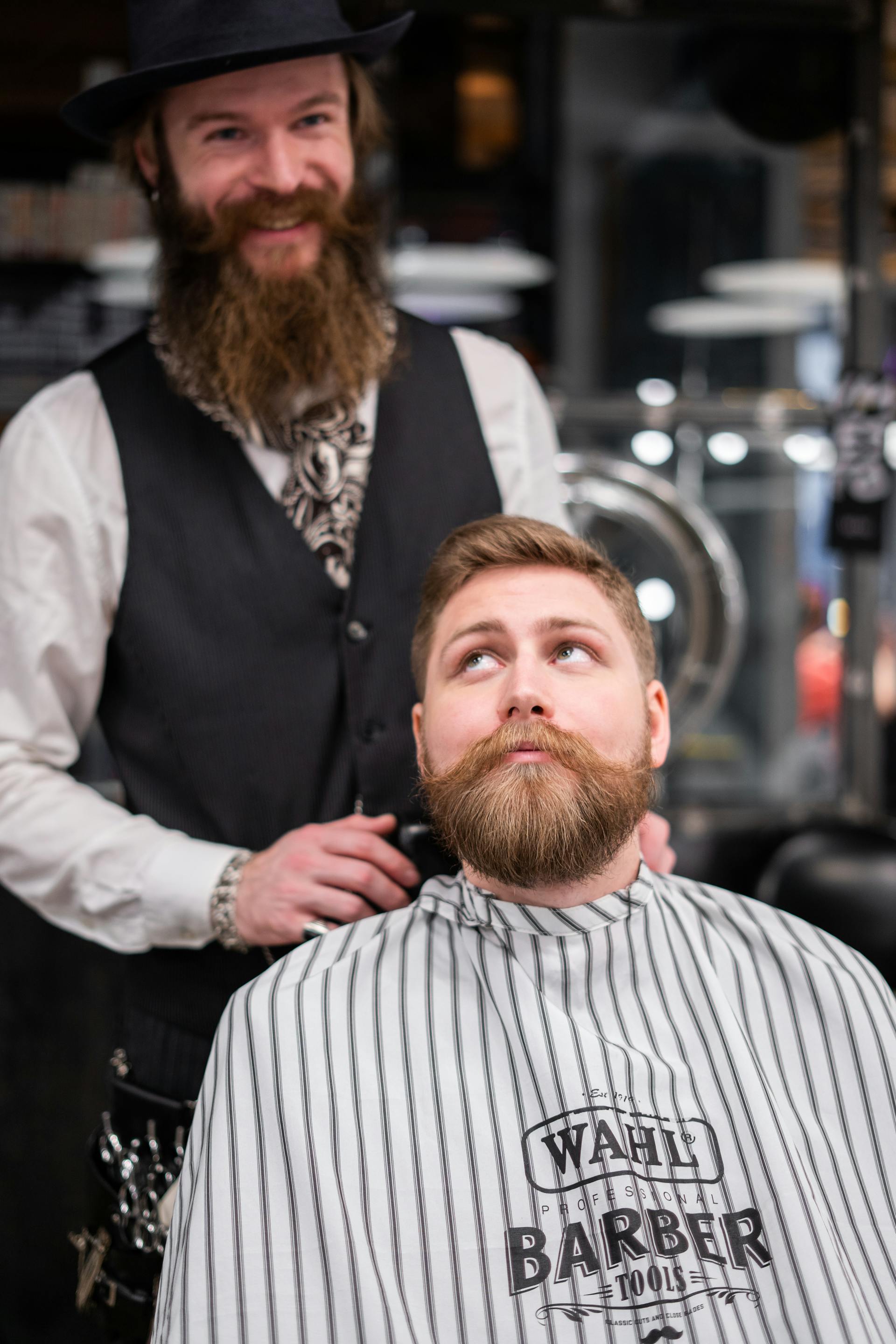 Un barbero sonríe de pie detrás de un cliente en su tienda | Fuente: Pexels