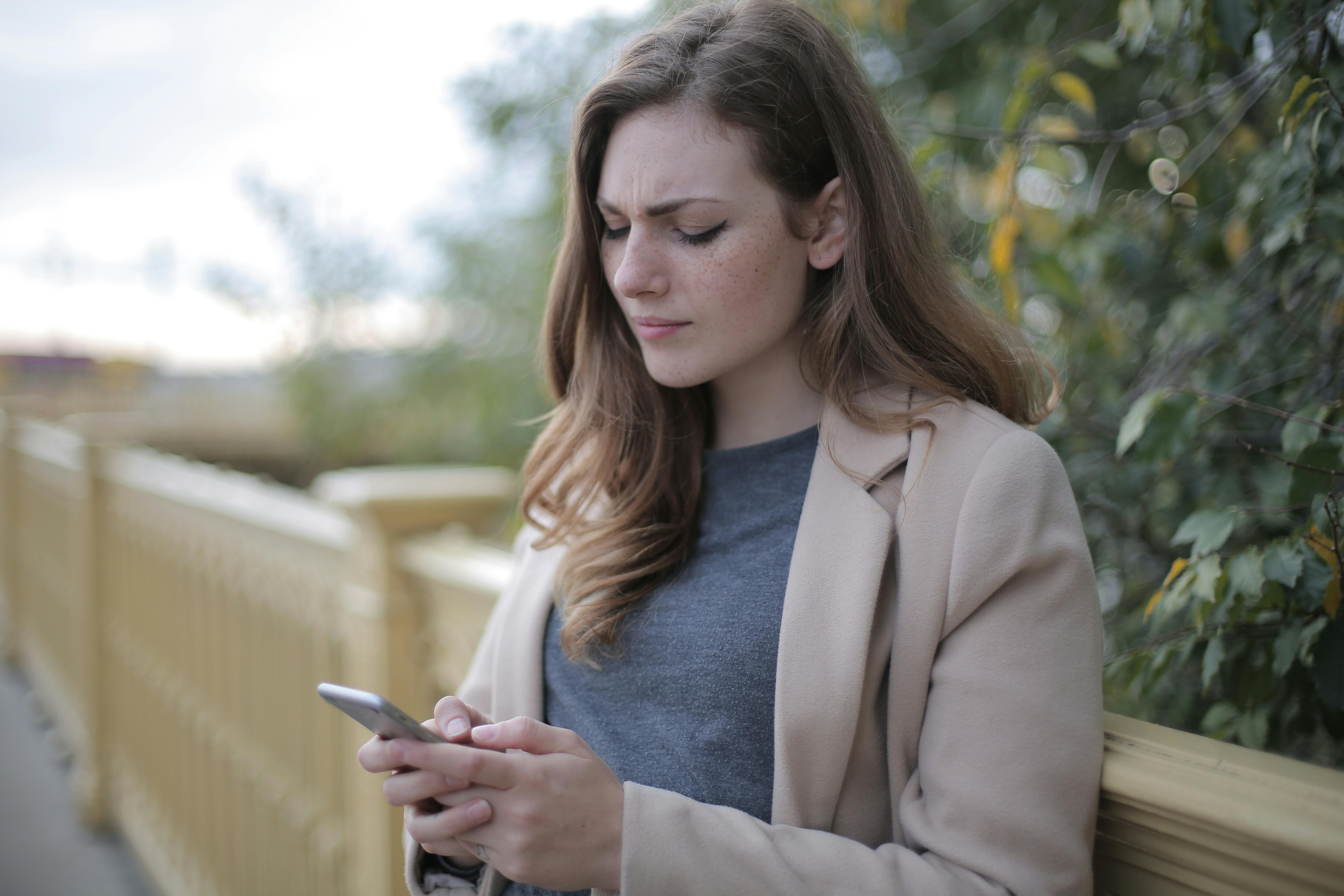 Una mujer infeliz leyendo algo en su teléfono | Fuente: Pexels