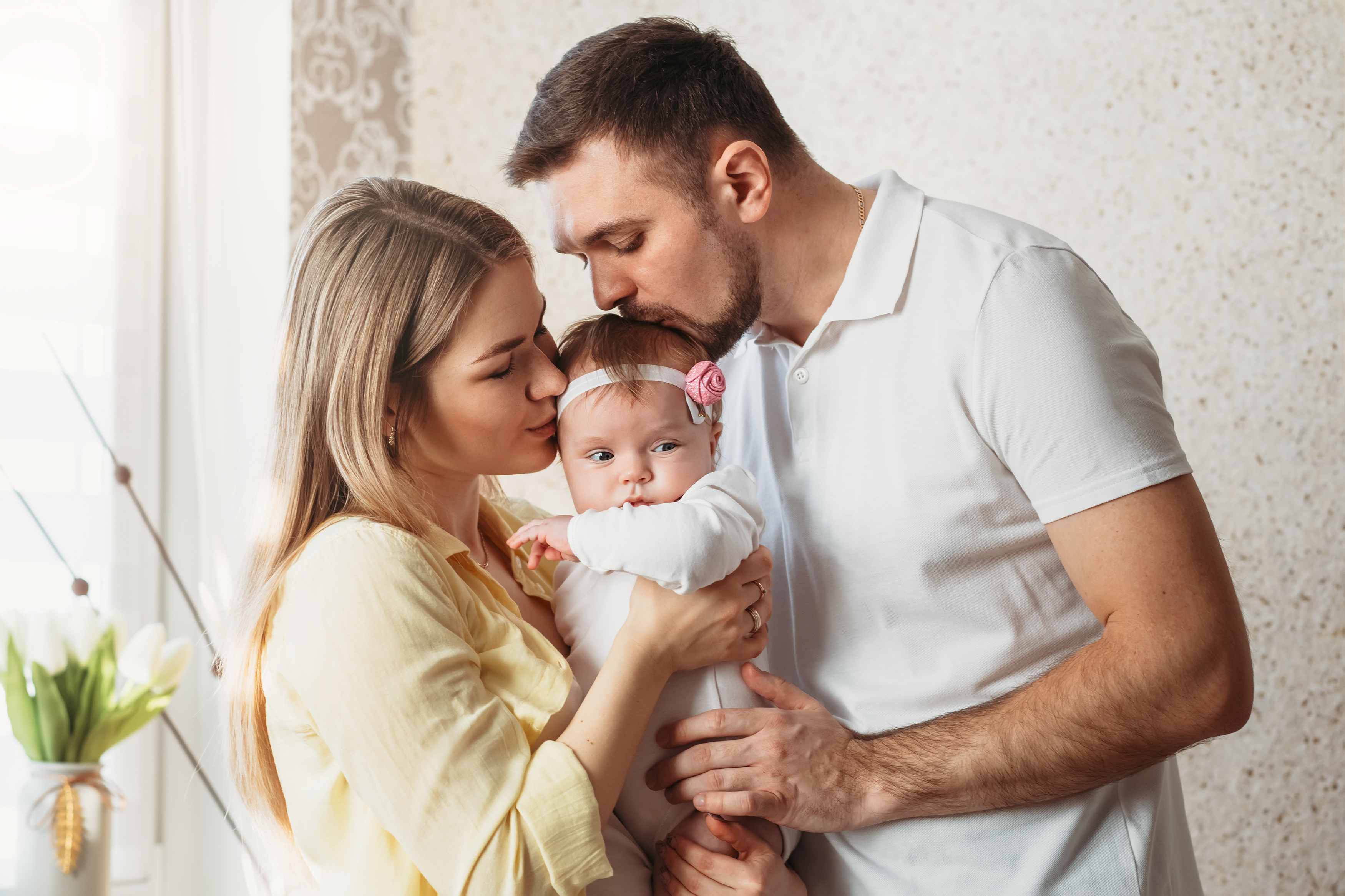 Unos padres primerizos besando a su bebé | Foto: Shutterstock