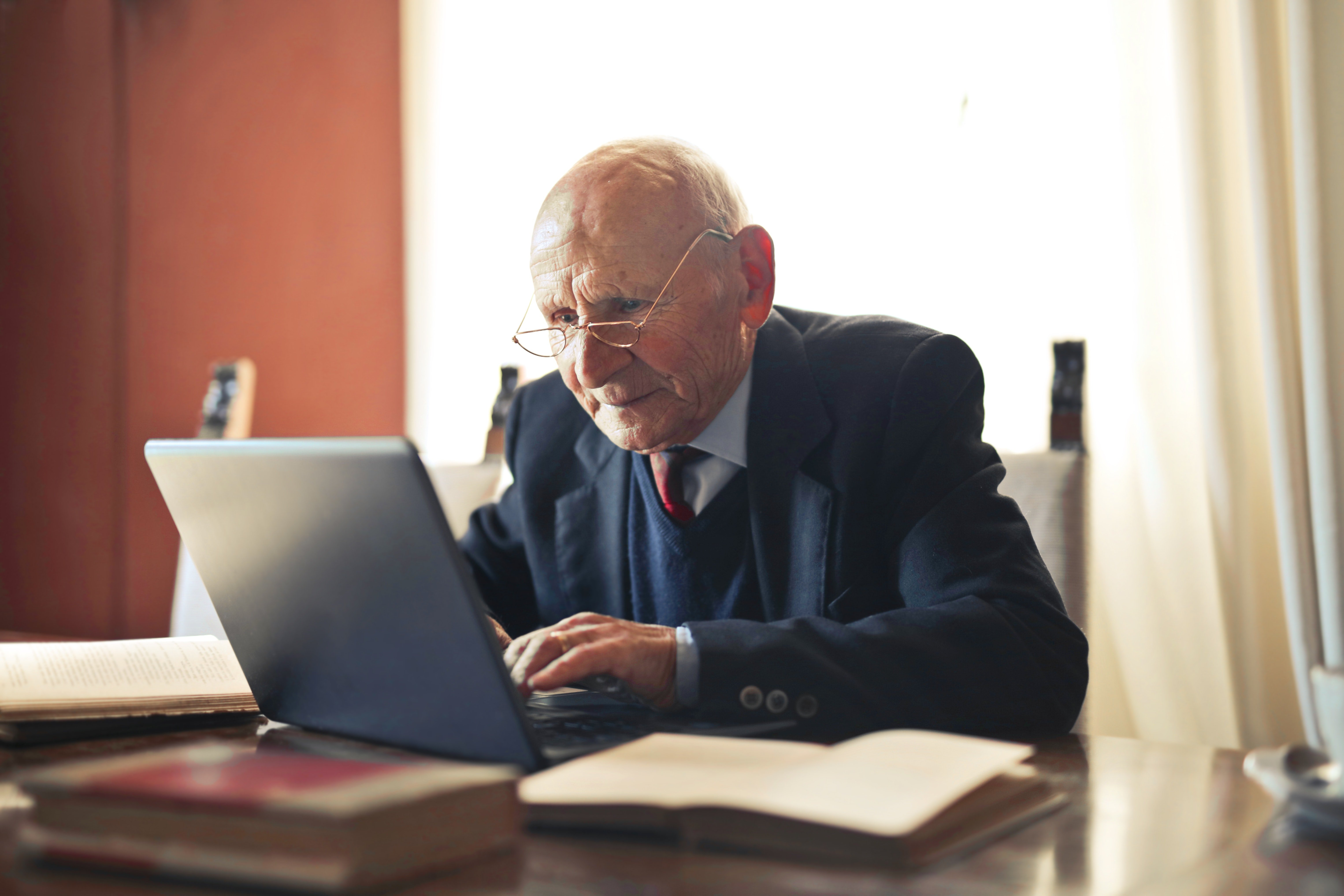 Hombre mayor sentado frente a una computadora | Foto: Pexels