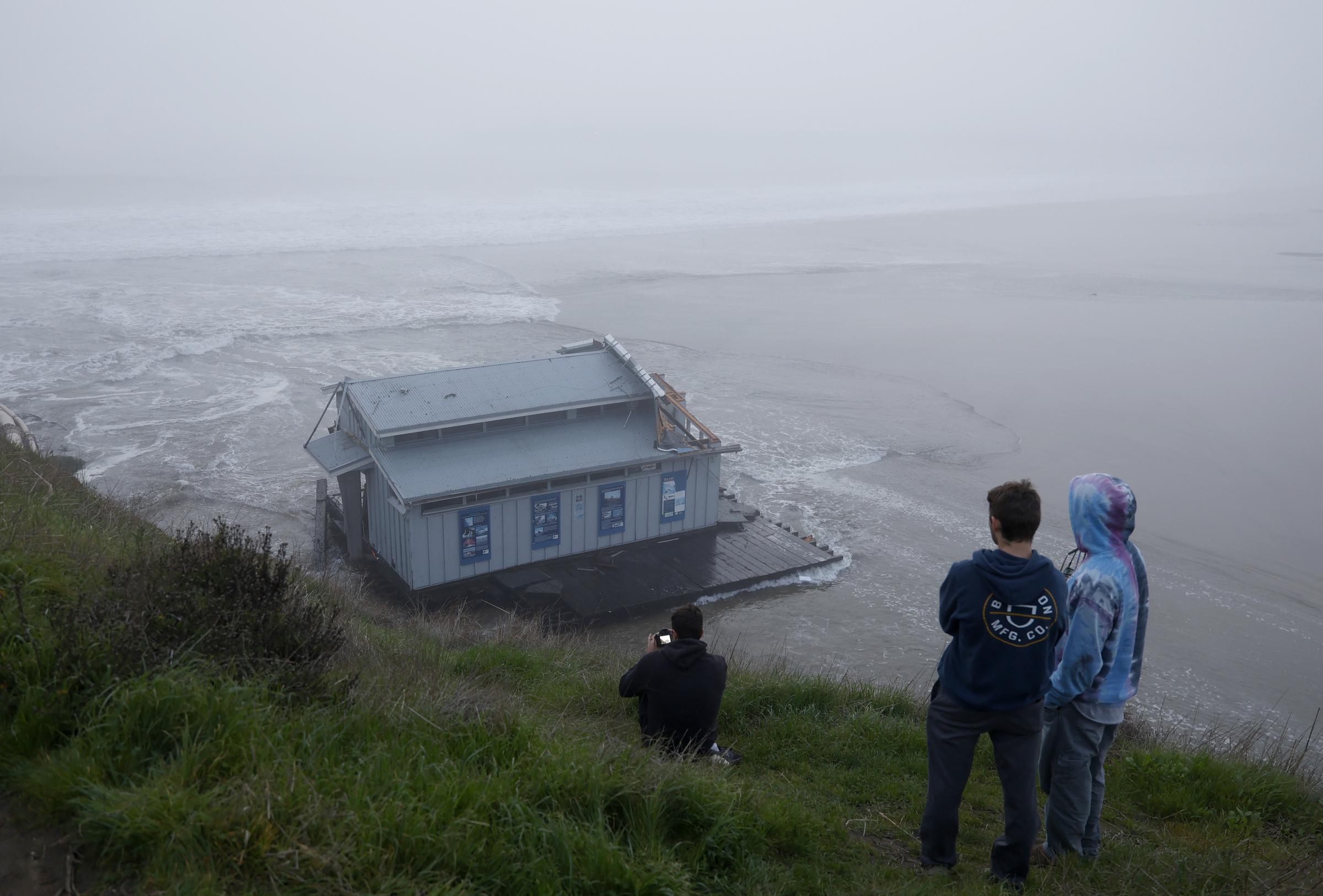 Un grupo de personas observa el muelle derrumbado en el embarcadero de Santa Cruz, California, el 23 de diciembre de 2024 | Fuente: Getty Images