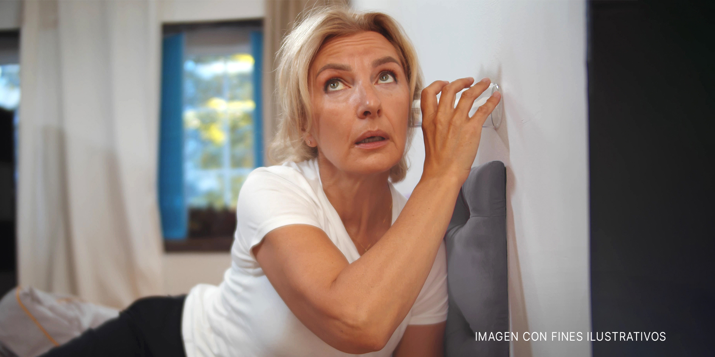 Una vecina entrometida escuchando a escondidas | Foto: Shutterstock