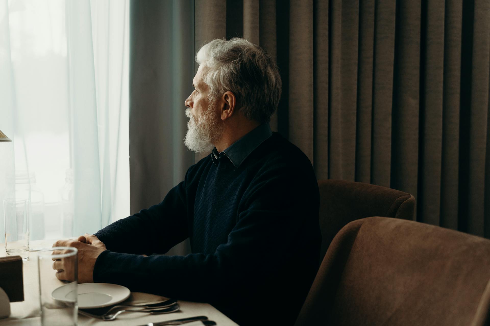 Un hombre mayor mirando por la ventana mientras habla | Fuente: Pexels