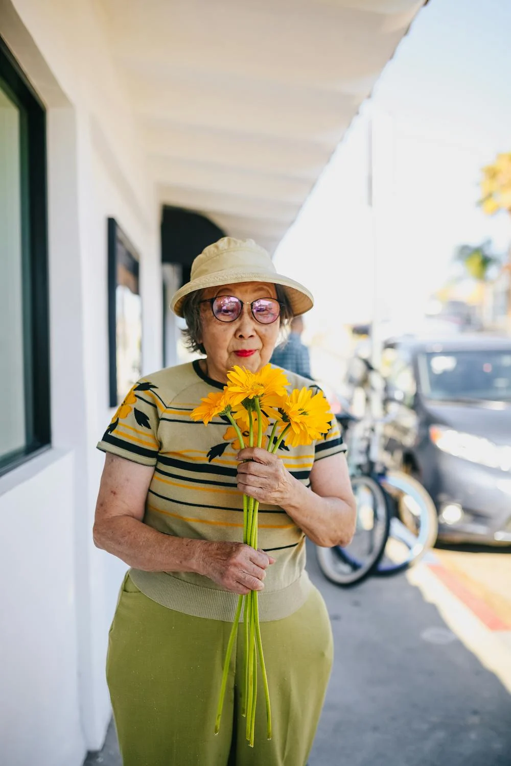 Una anciana sonriente con flores en la mano | Fuente: Pexels