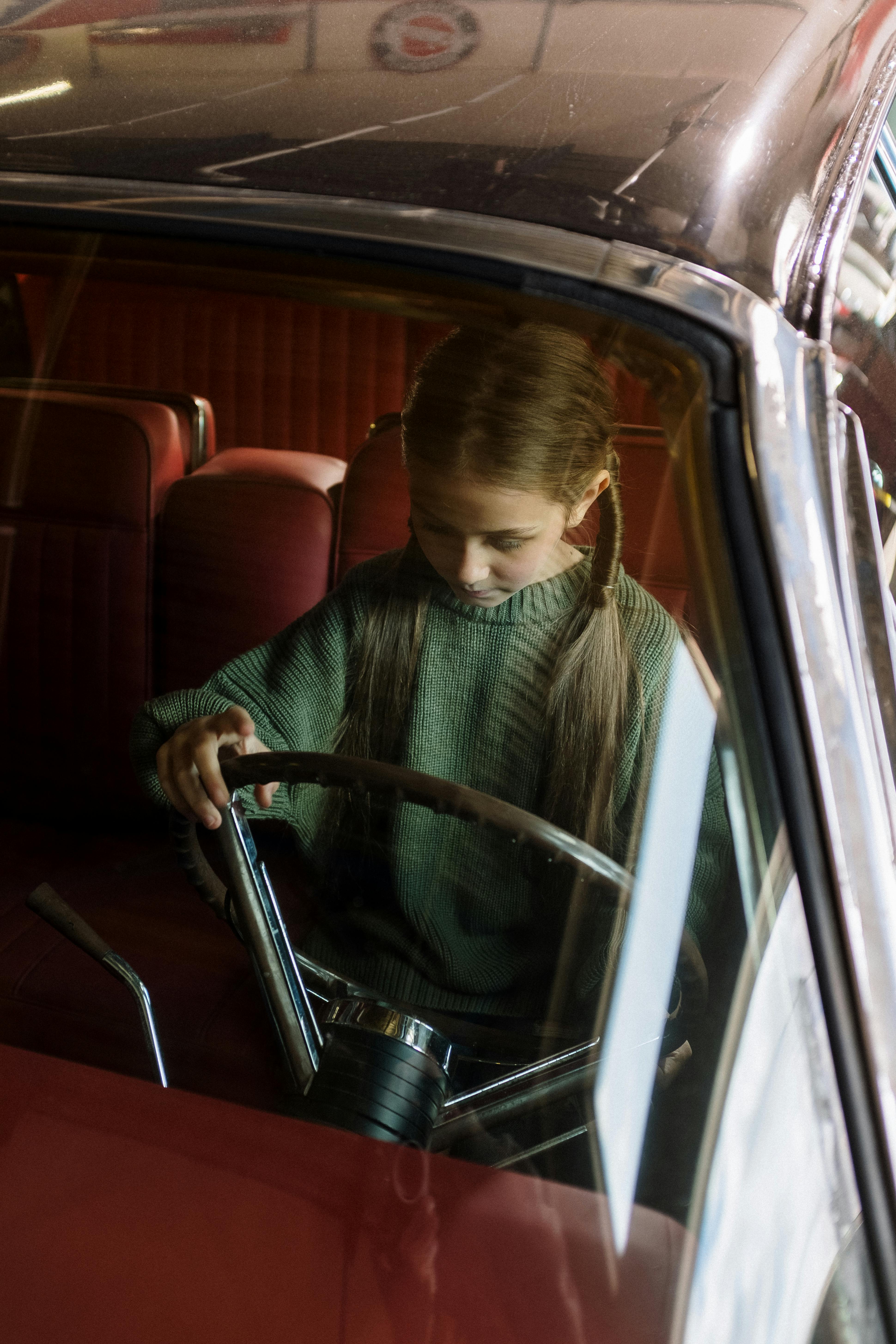 Una niña jugando en un coche aparcado | Fuente: Pexels