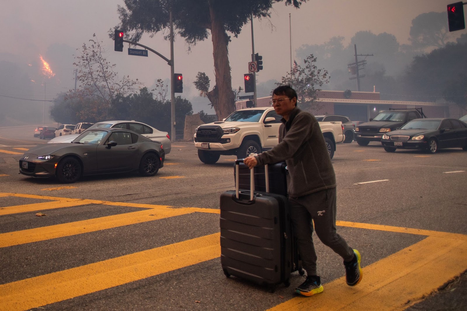 Un hombre evacua a lo largo de Sunset Boulevard mientras el fuego arde en medio de una fuerte tormenta de viento el 7 de enero de 2025, en el barrio de Pacific Palisades de Los Ángeles, California. | Fuente: Getty Images