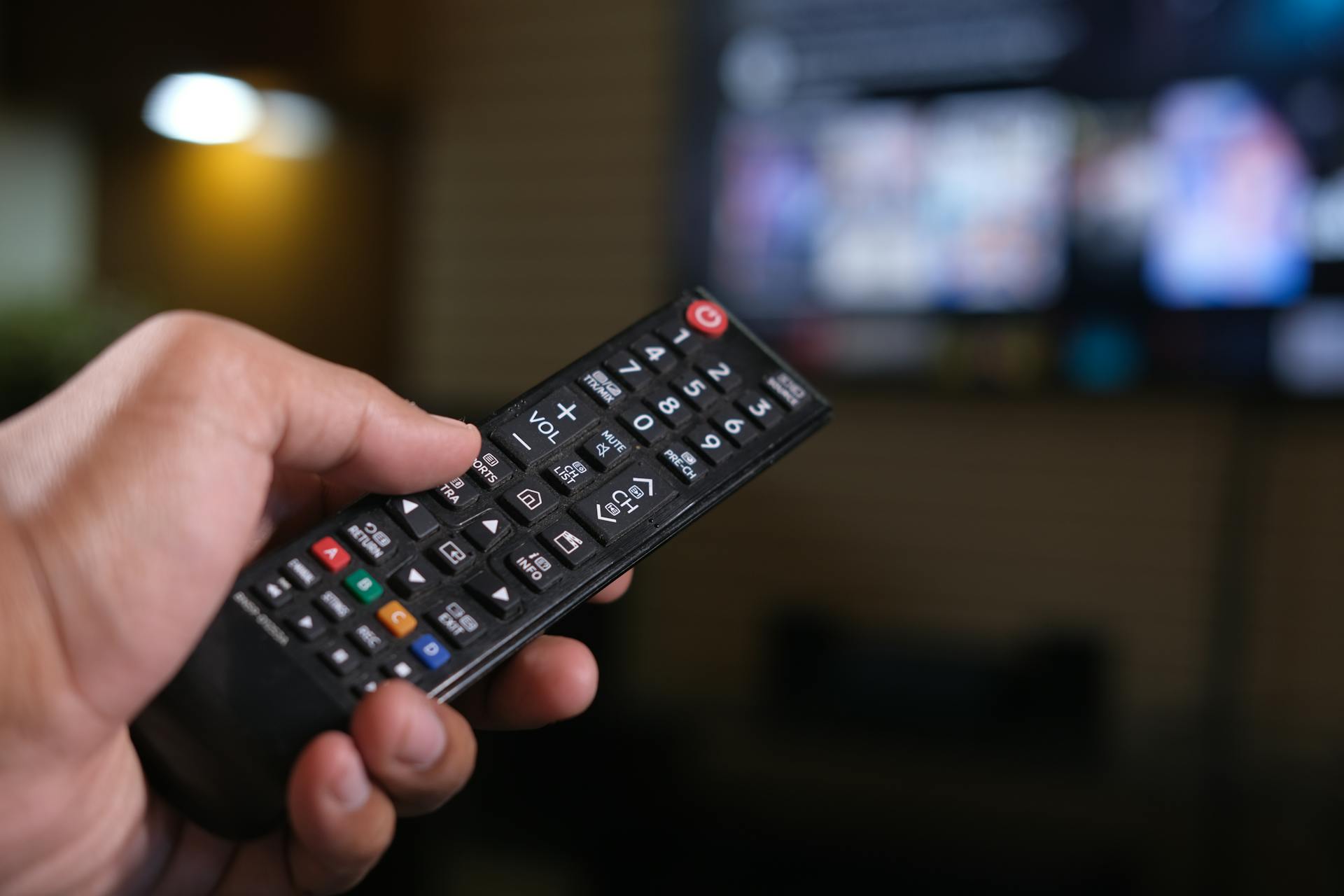Hombre sujetando el mando a distancia de un televisor | Fuente: Pexels