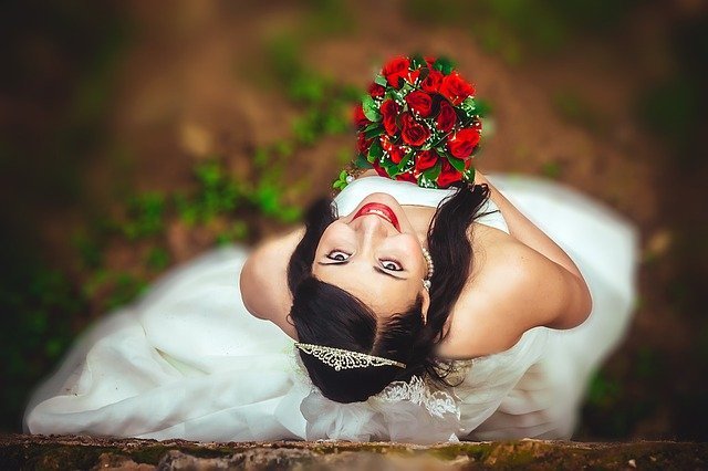 Novia risueña sosteniendo su ramo de flores el día de su boda. Fuente: Pixabay