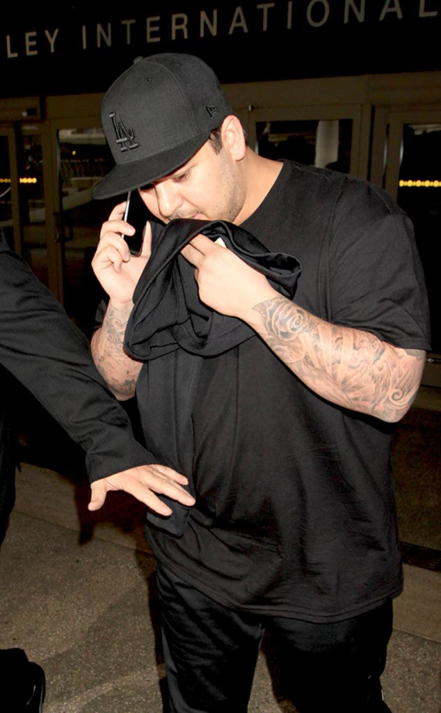 Rob Kardashian fue fotografiado a la salida de un aeropuerto, tapándose parte de la cara con una camiseta negra mientras hablaba por el celular. La imagen nos recuerda su difícil relación con la atención de los paparazzi, algo que, según reveló más tarde, había influido en su decisión de no asistir a la boda de Kim Kardashian en 2014. | Fuente: Getty Images.