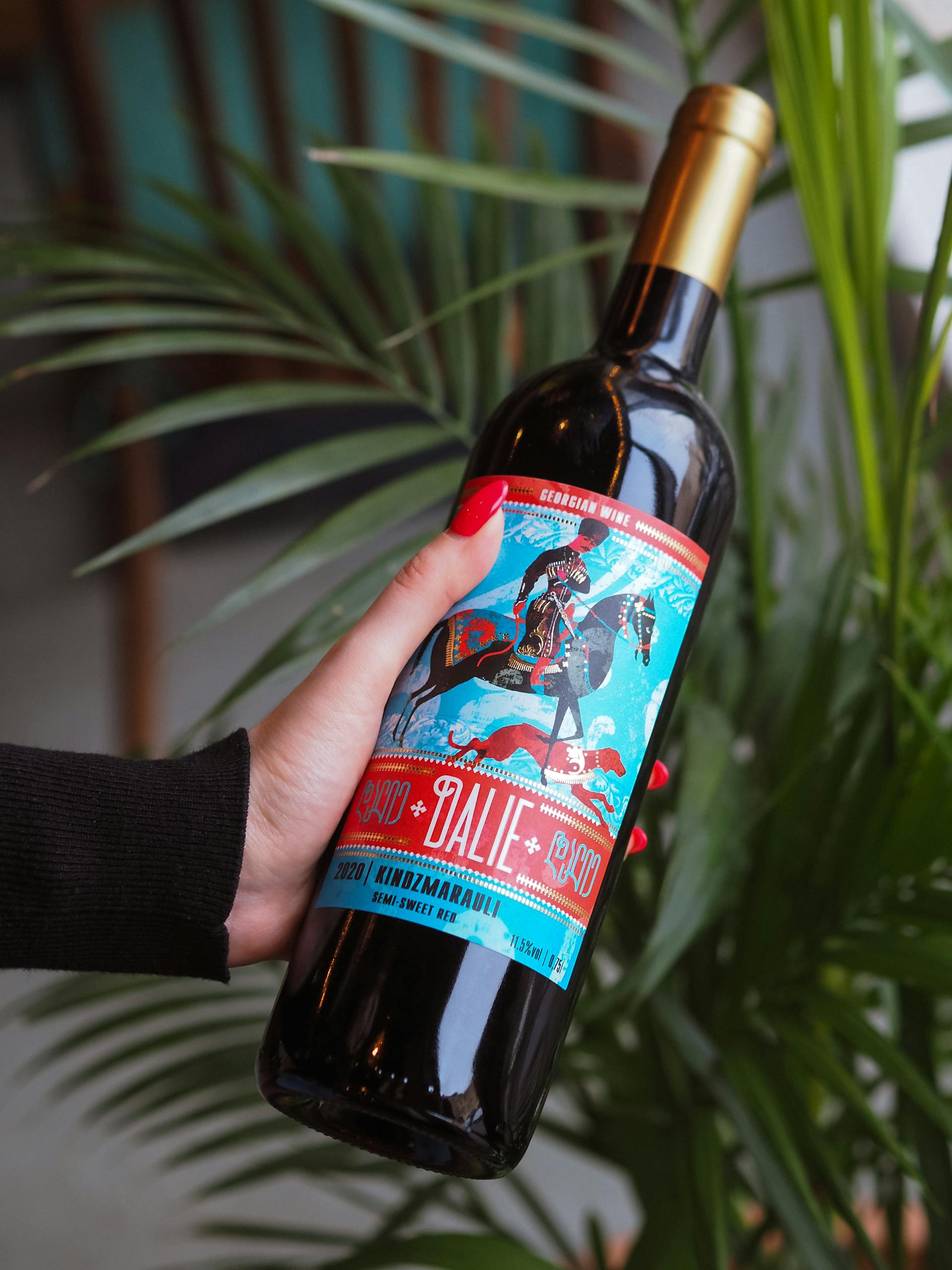 Primer plano de una mujer sosteniendo una botella de vino | Fuente: Pexels