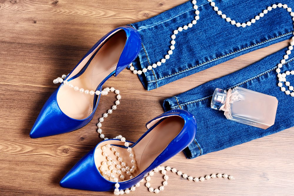 Zapatos azules, perfume y abalorios sobre la mesa. | Foto: Shutterstock