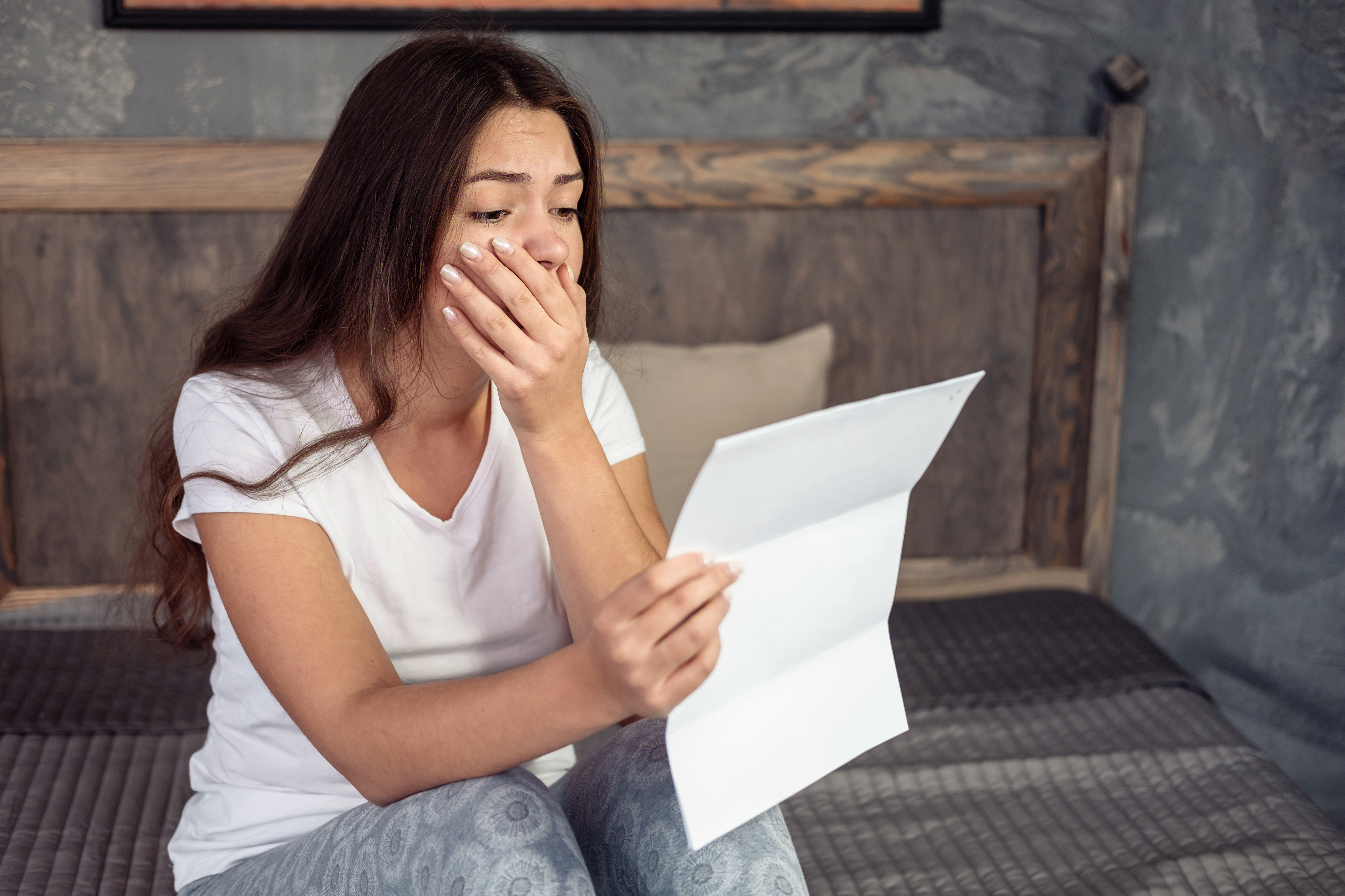 Una joven conmocionada leyendo una carta | Fuente: Shutterstock