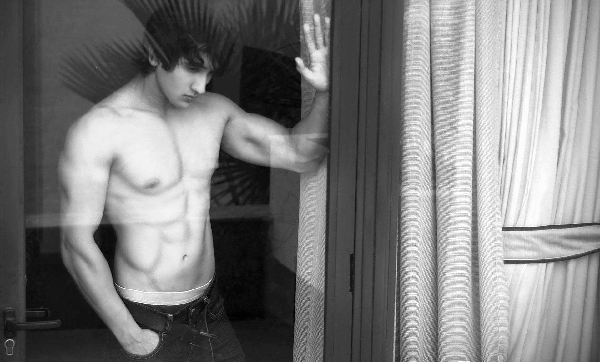 Un hombre sin camiseta cerca de una ventana | Fuente: Pexels