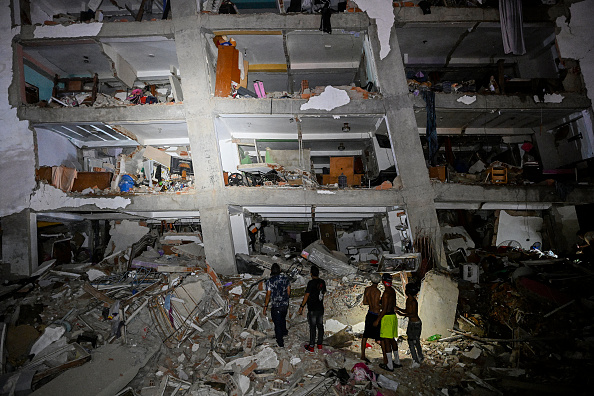 Personas permanecen entre los escombros cerca de un edificio dañado tras el terremoto ocurrido en Catia La Mar, estado La Guaira, a unos 30 kilómetros al noroeste de Caracas, durante la madrugada del 25 de junio de 2026.