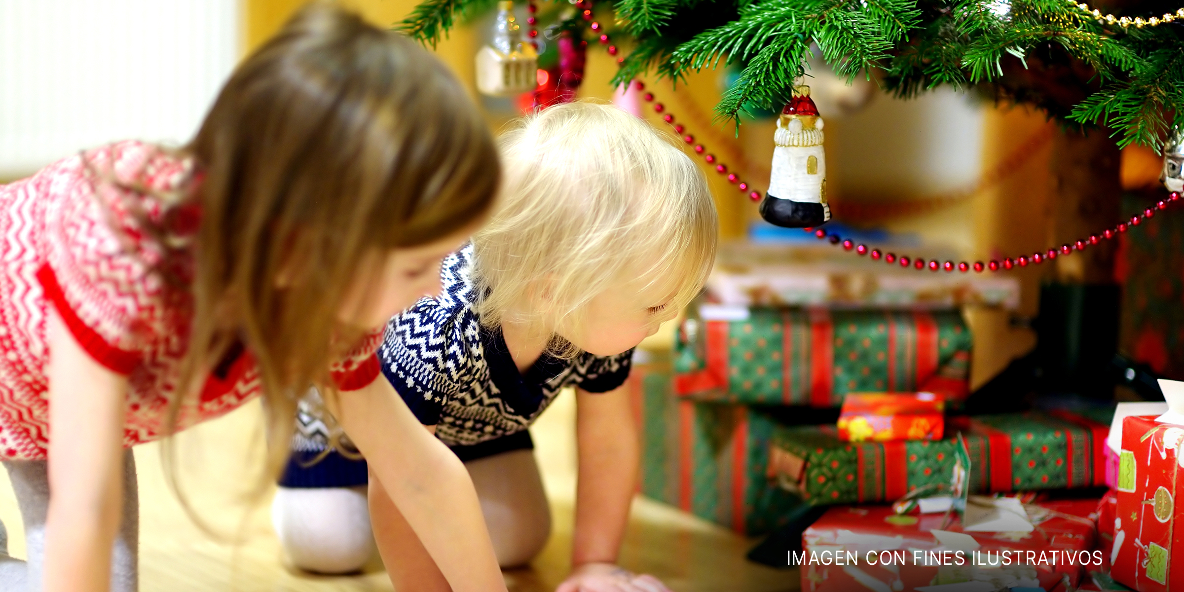 Niños mirando los regalos bajo el árbol de Navidad | Foto: Shutterstock