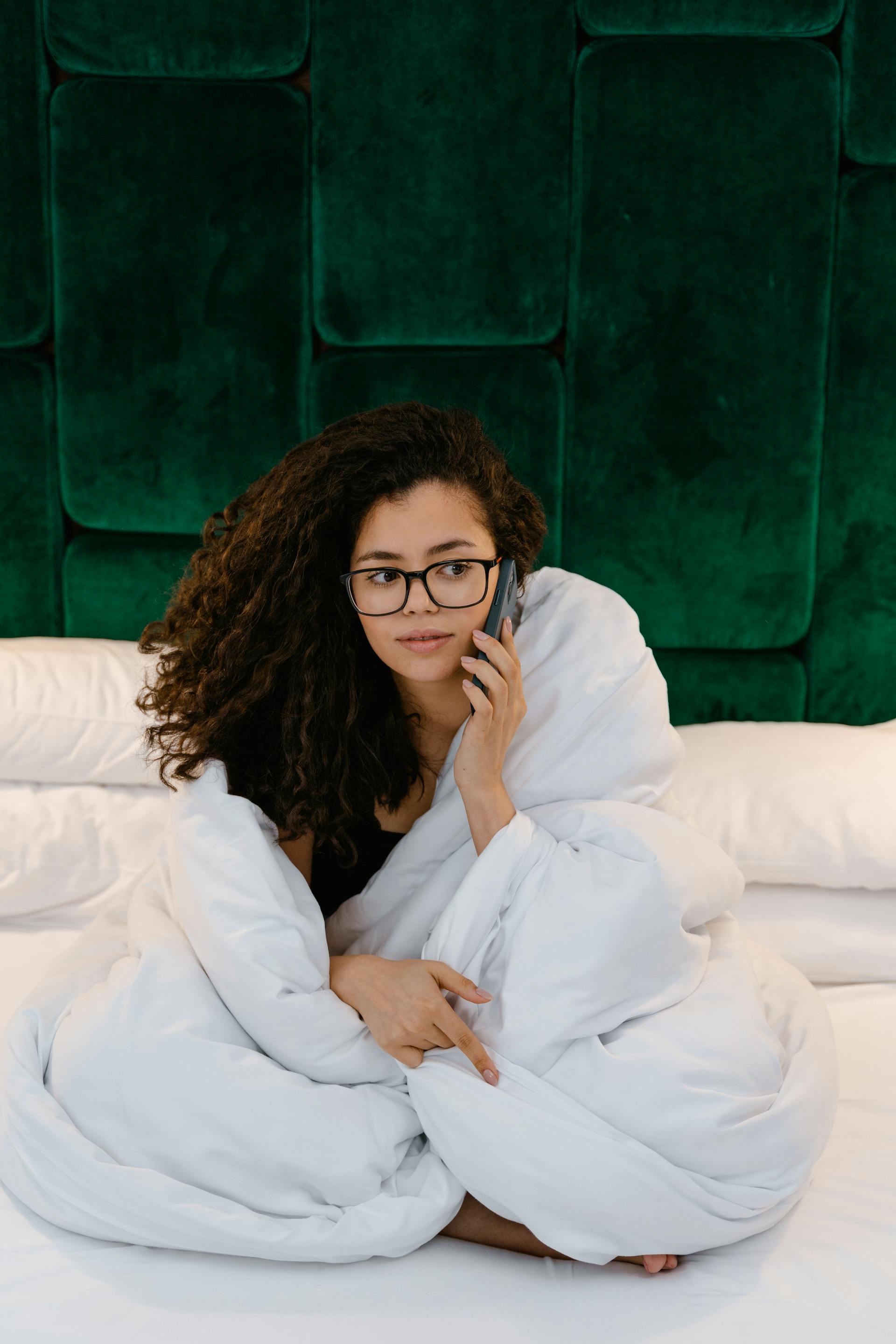 Una mujer en la cama respondiendo a una llamada telefónica | Fuente: Pexels