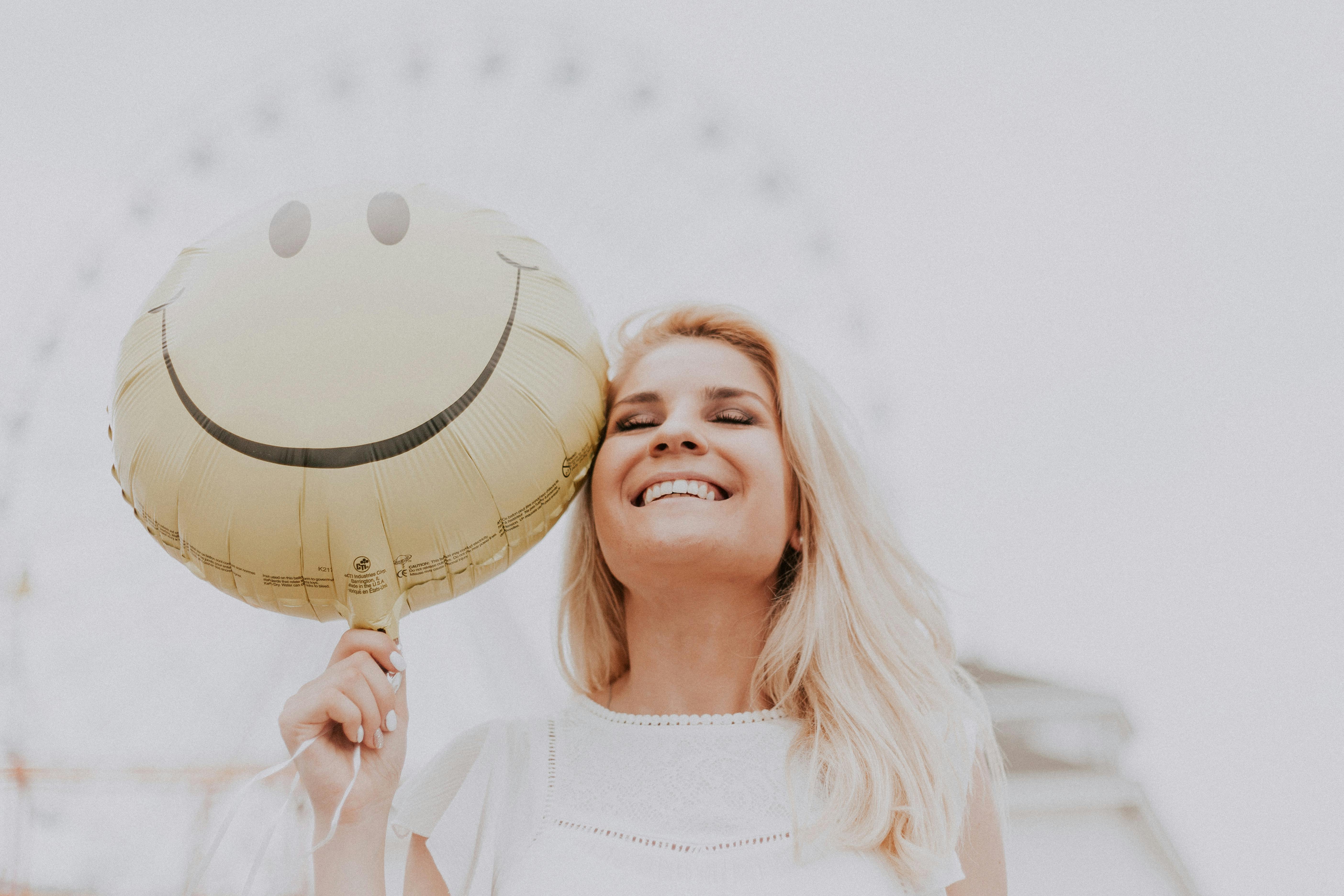 Mujer sujetando un globo sonriente | Foto: Pexels