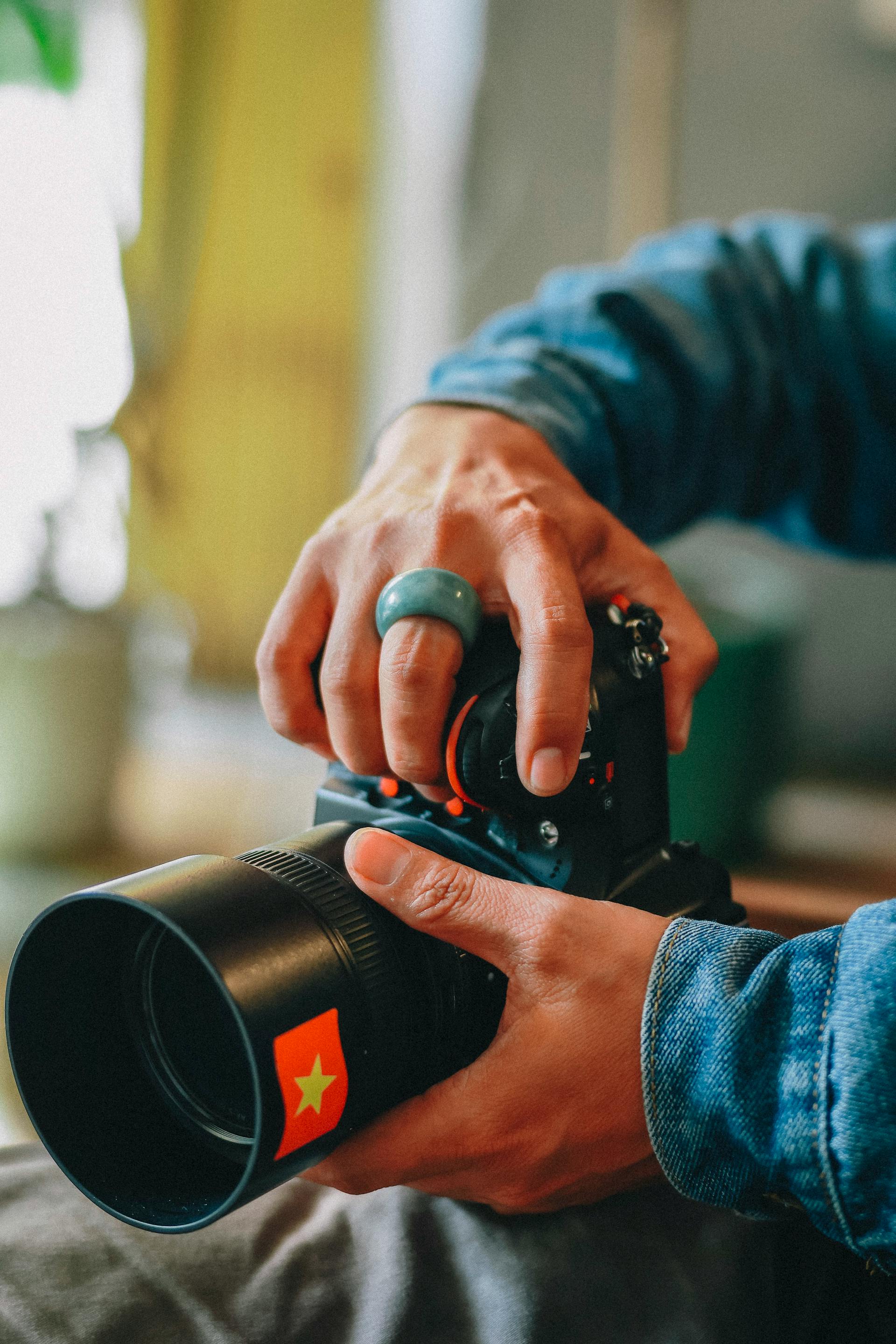 Primer plano de un fotógrafo ajustando el objetivo de su cámara | Fuente: Pexels