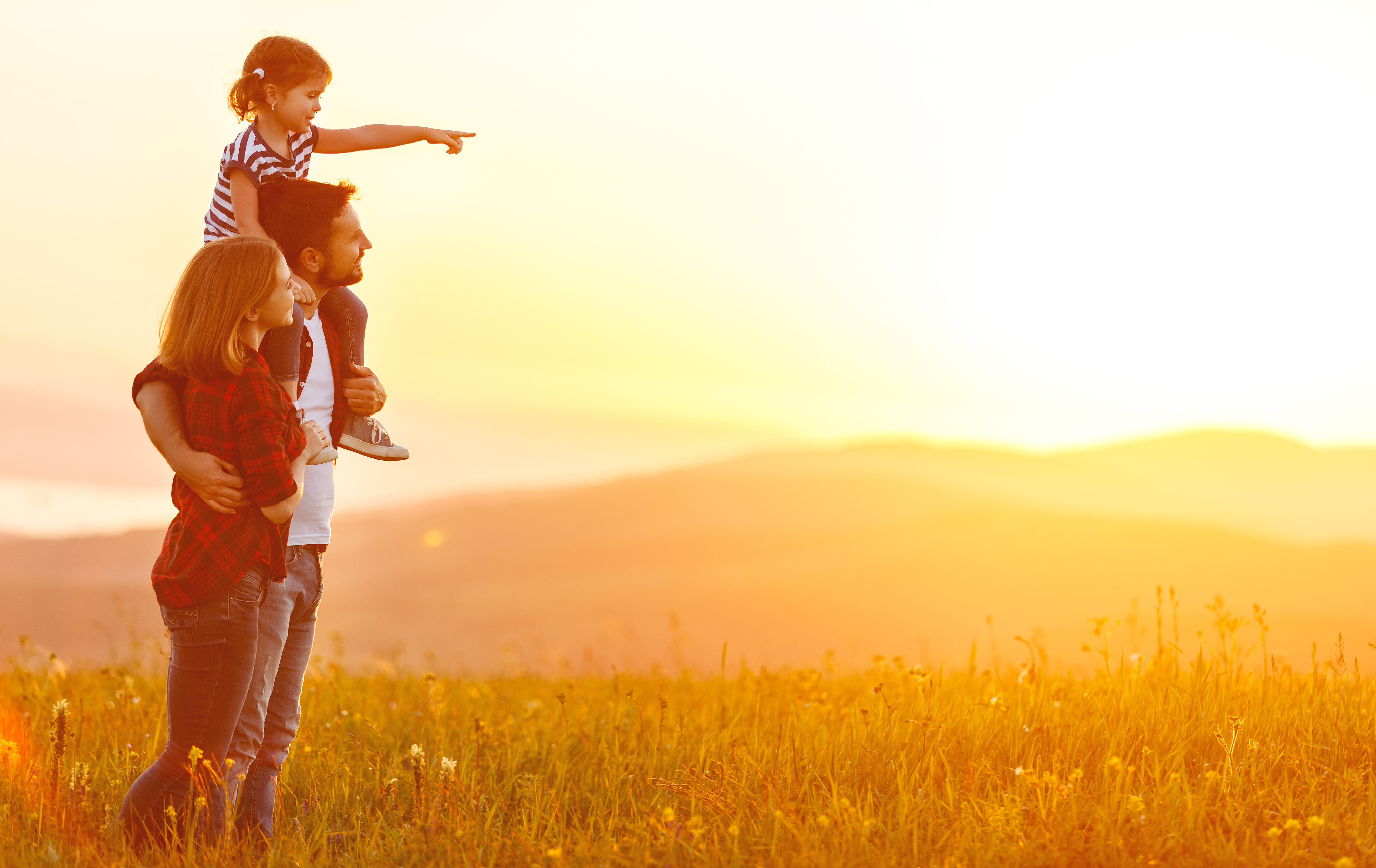 Pareja viendo la puesta de sol con su hija pequeña | Foto: Shutterstock