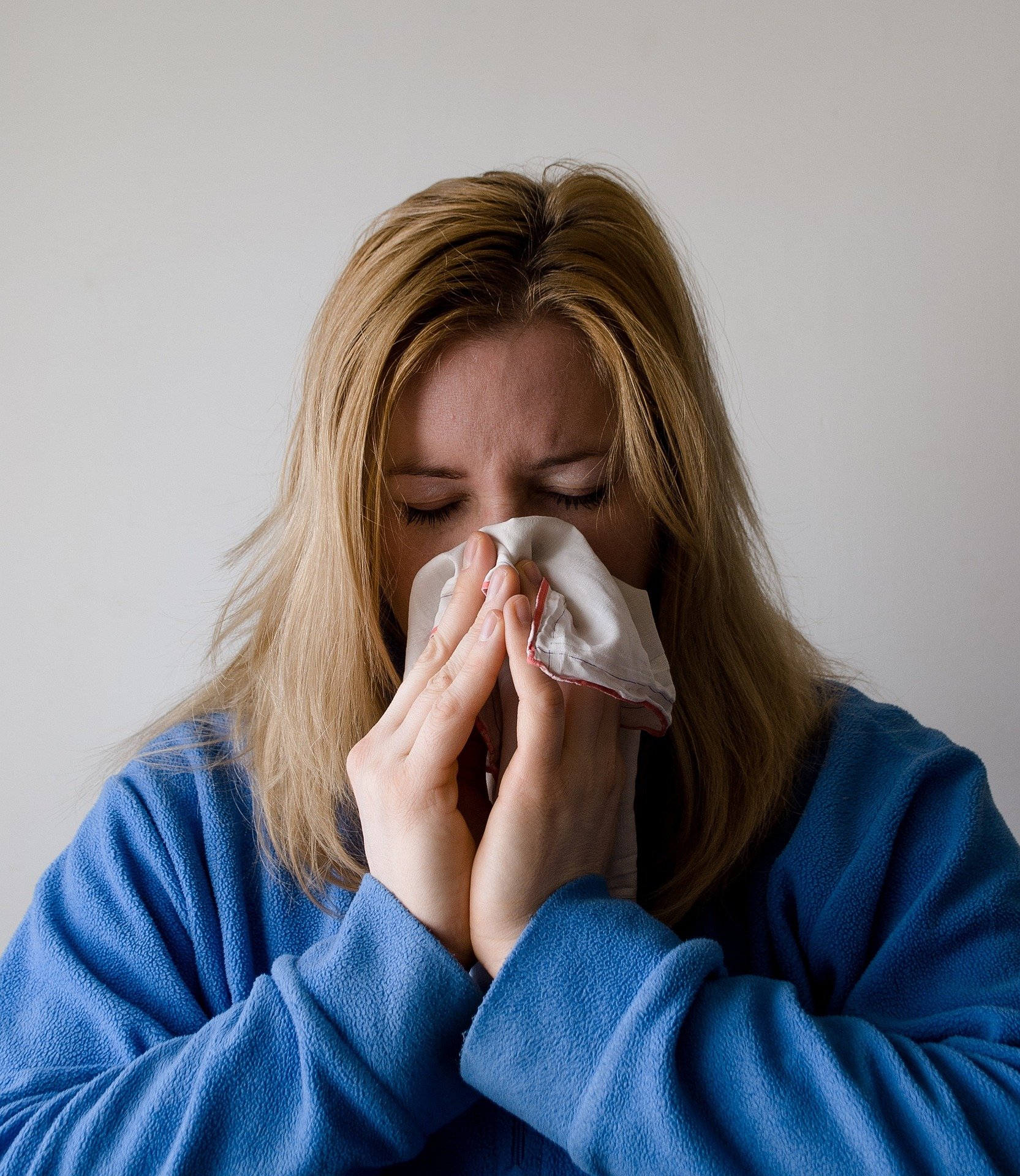 Mujer con resfriado se sopla la nariz. Fuente: Pixabay