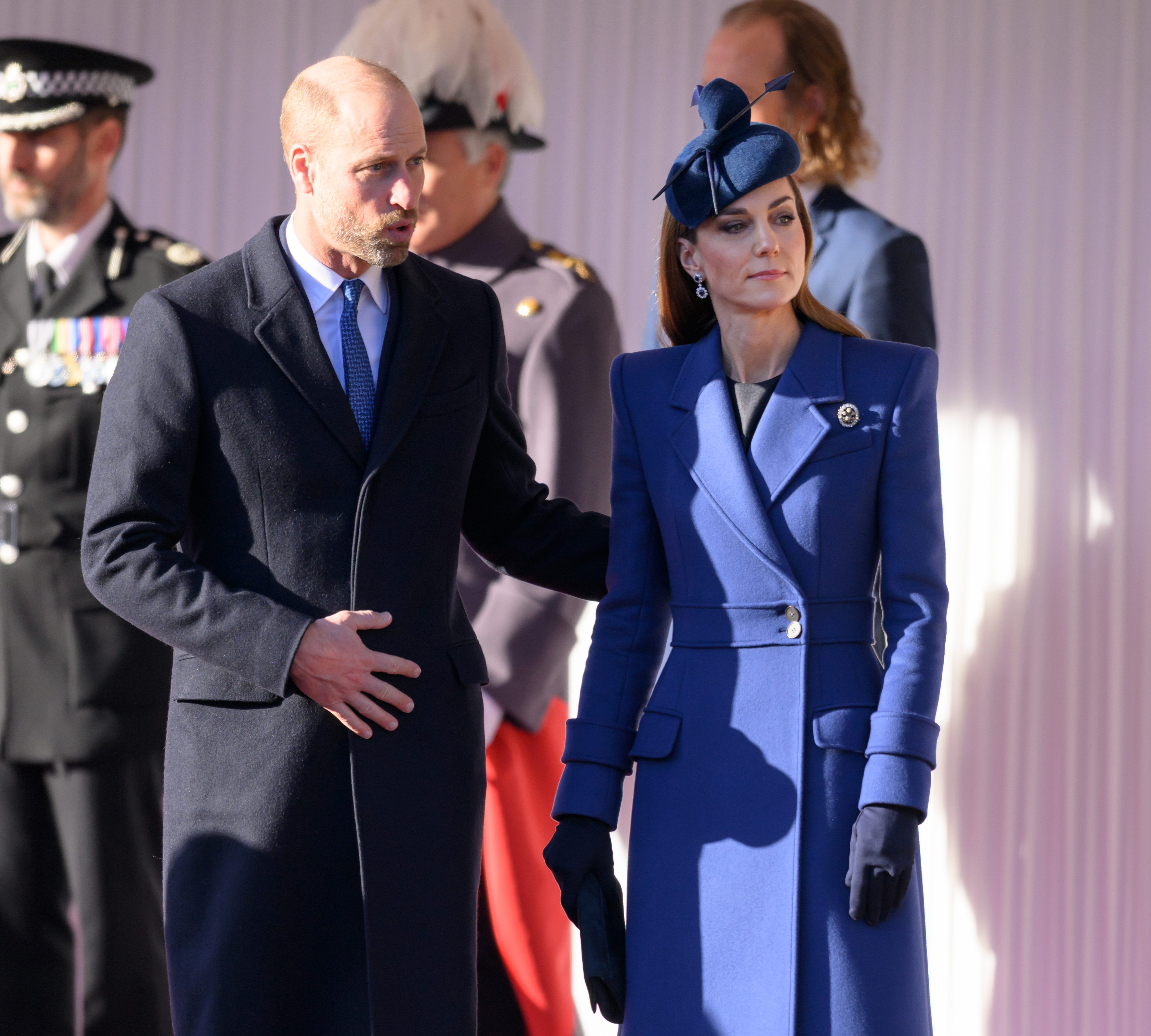 El príncipe William y Catherine, princesa de Gales, posan juntos durante la bienvenida ceremonial en el castillo de Windsor el 3 de diciembre de 2025, al inicio de la visita de Estado alemana. Catherine luce un elegante vestido-abrigo azul cobalto con hombros estructurados, solapas con muescas y cinturón, combinado con un tocado a juego en forma de lazo, guantes azul oscuro y un histórico broche de diamantes. William viste un abrigo oscuro y corbata azul. | Fuente: Getty Images
