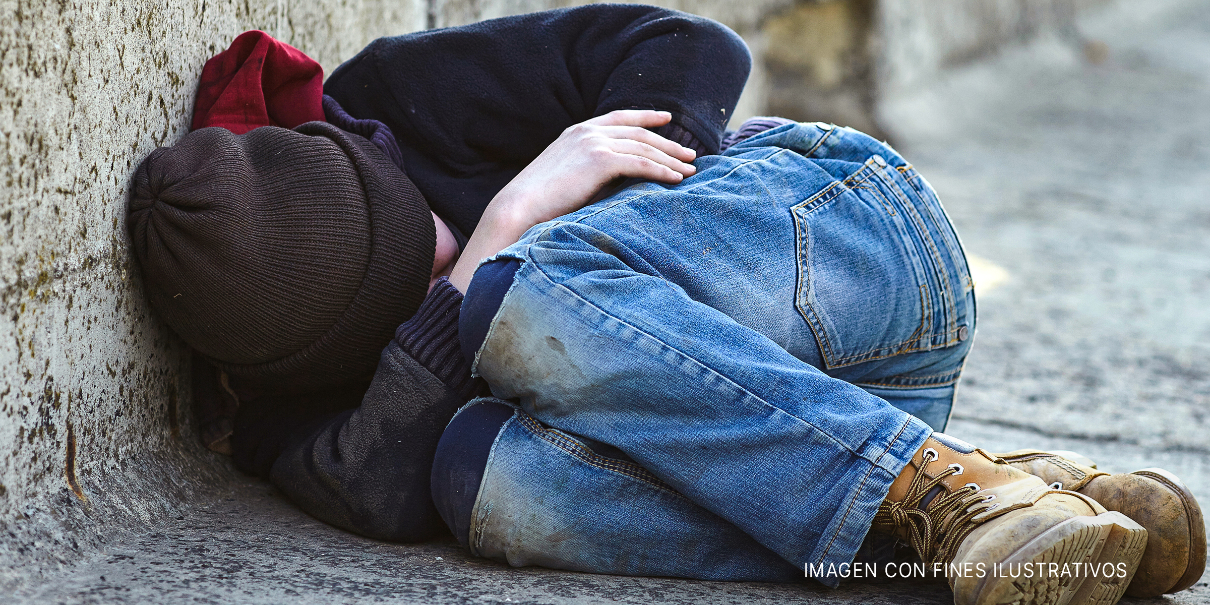 Un niño acurrucado mientras duerme en la calle | Foto: Shutterstock