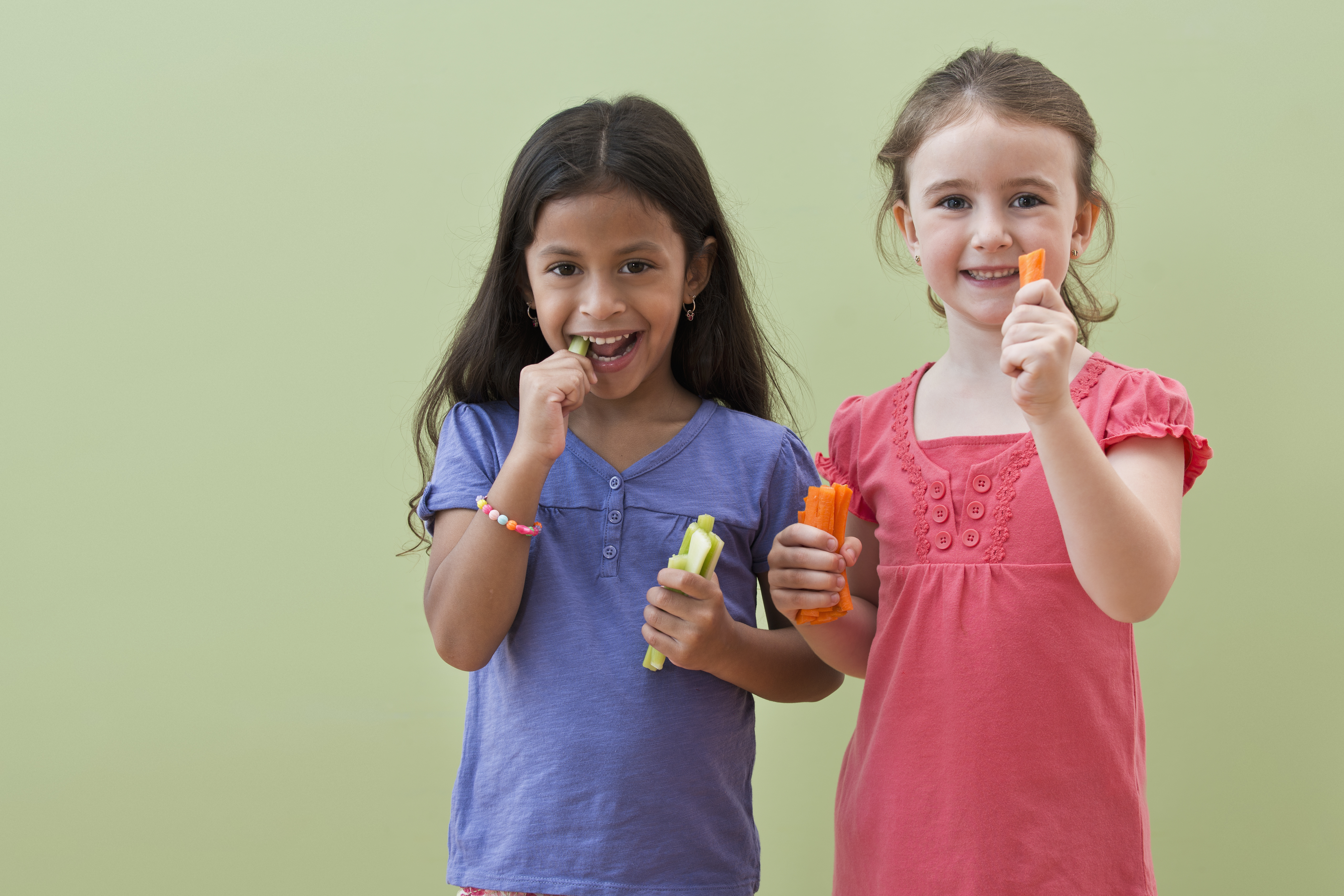 Niñas comiendo palitos de verdura juntas | Foto: Getty Images