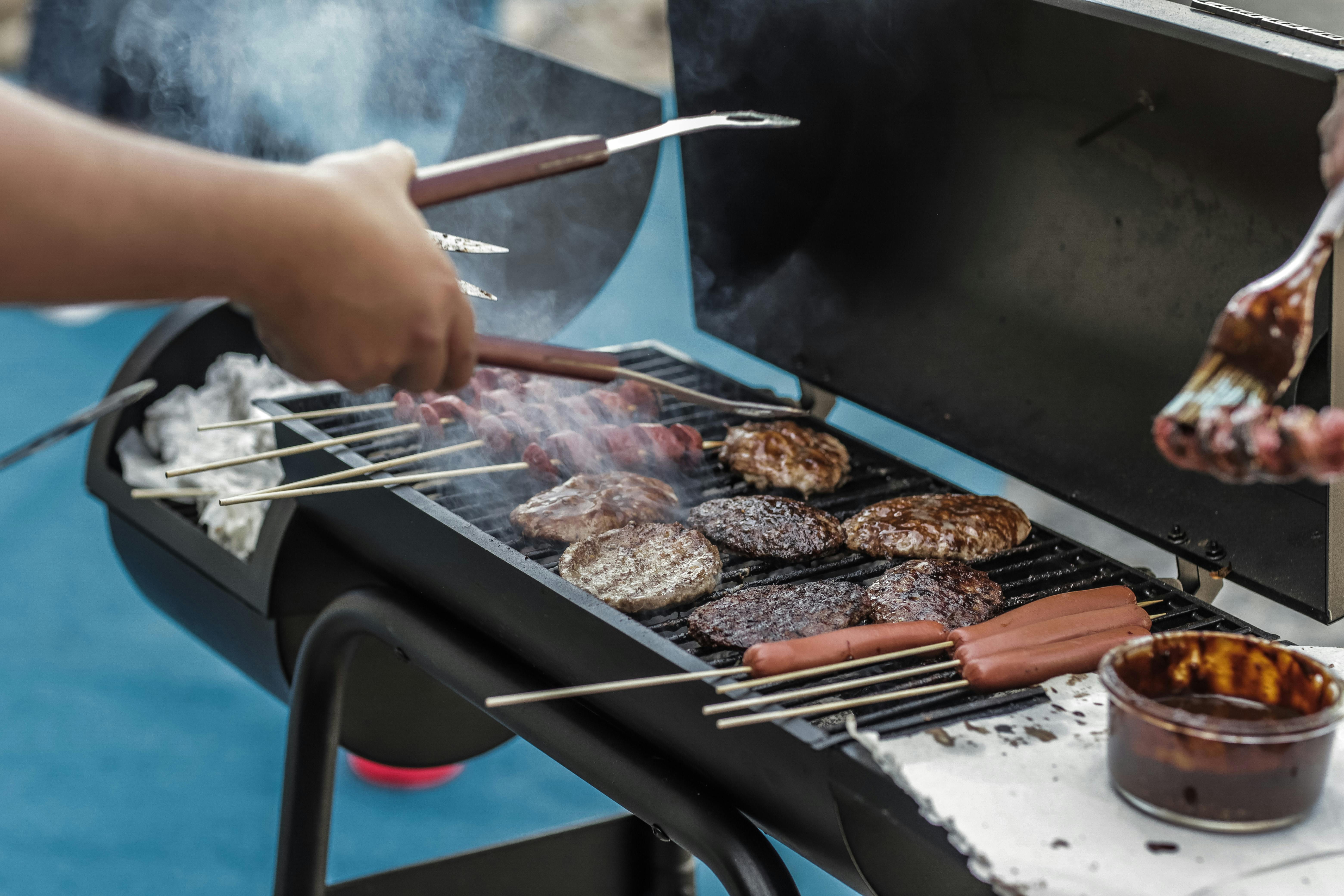 Un hombre asa salchichas y carne | Fuente: Pexels