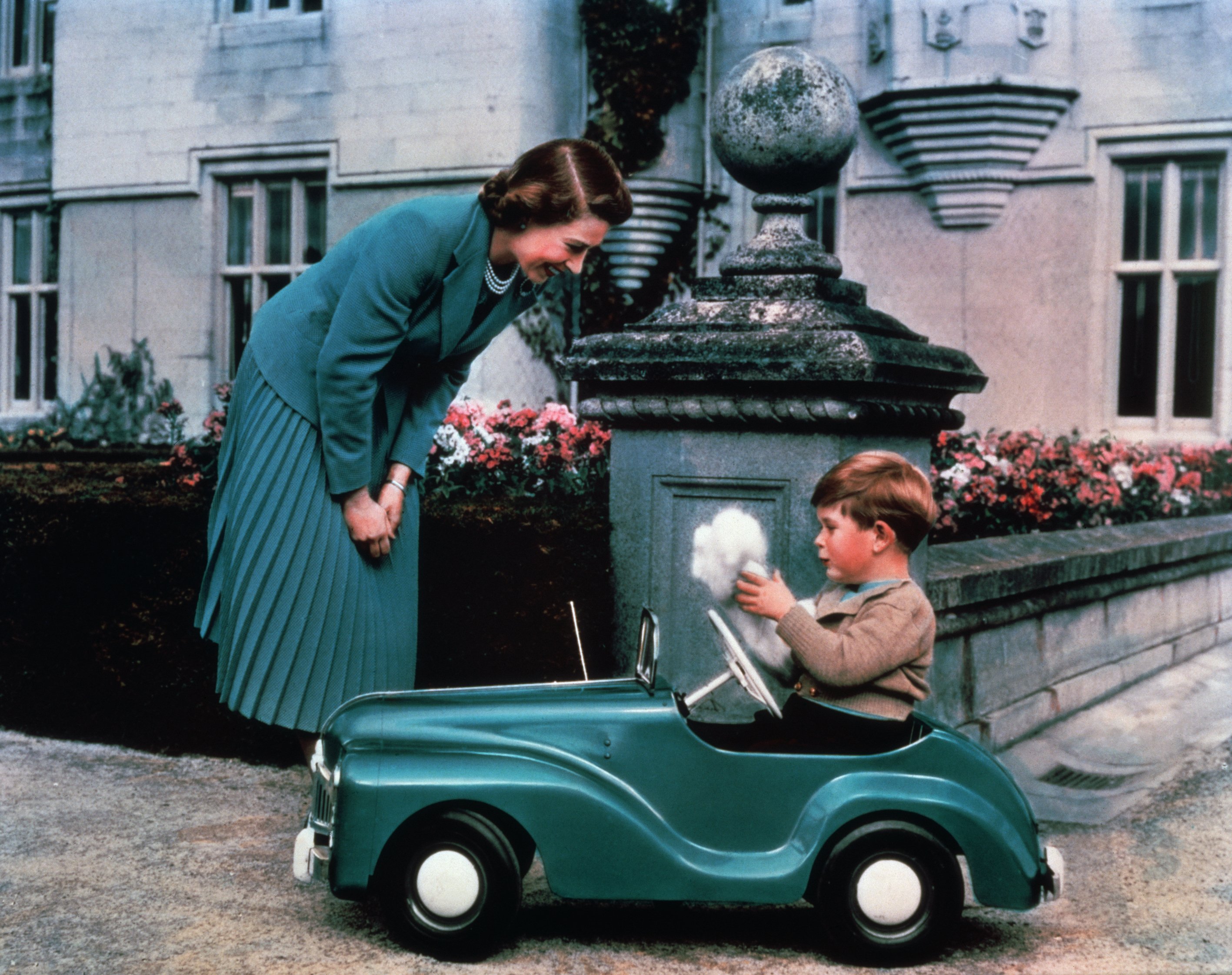 La reina Elizabeth II observa a su hijo, el príncipe Charles, conducir un coche de juguete por los terrenos del castillo de Balmoral, alrededor de 1952 | Foto: Getty Images