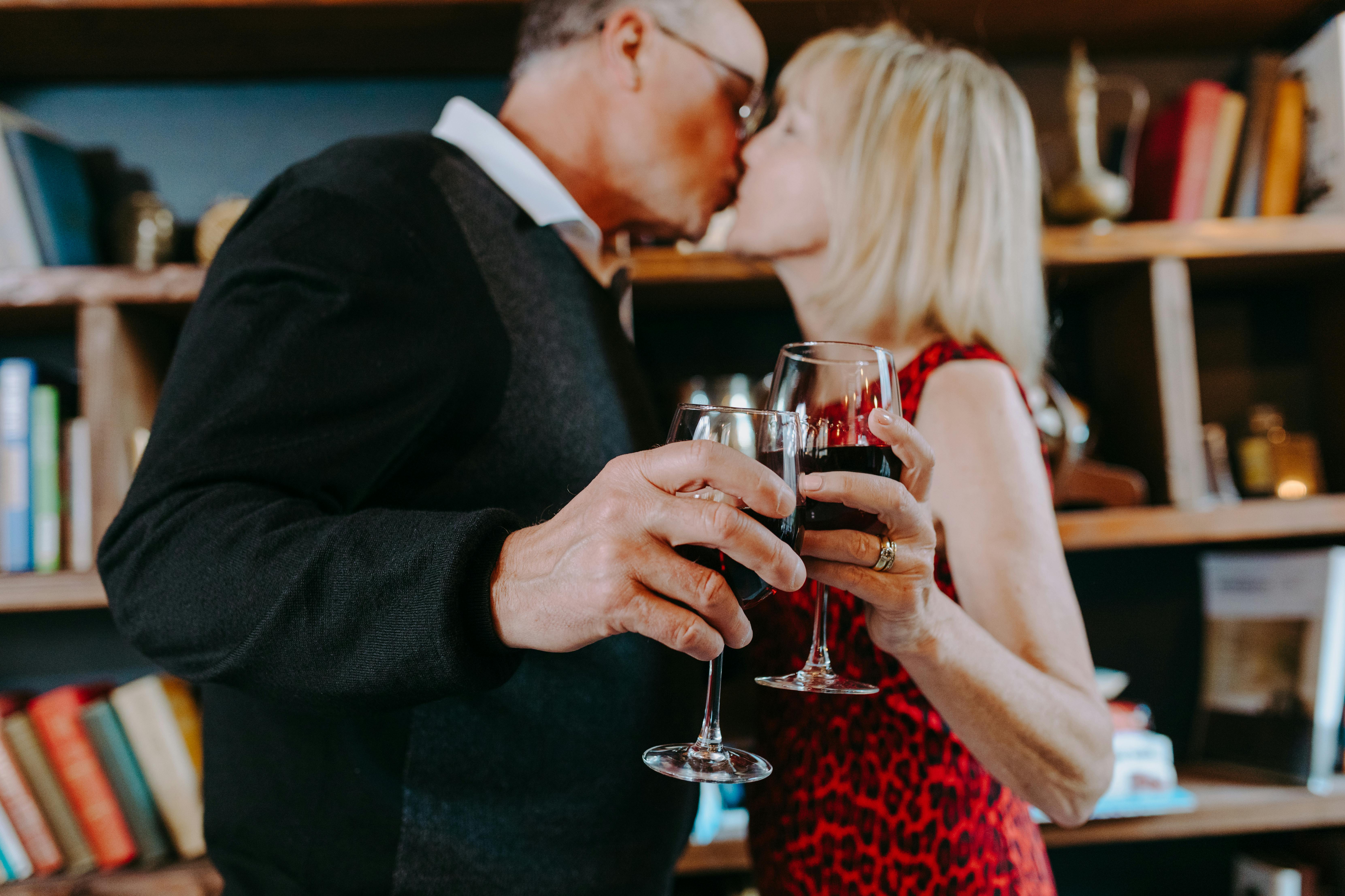 Una pareja compartiendo un brindis y un beso | Fuente: Pexels