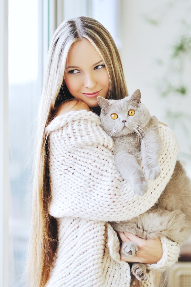 Mujer con suéter y un gato cargado. | Foto: Shutterstock.