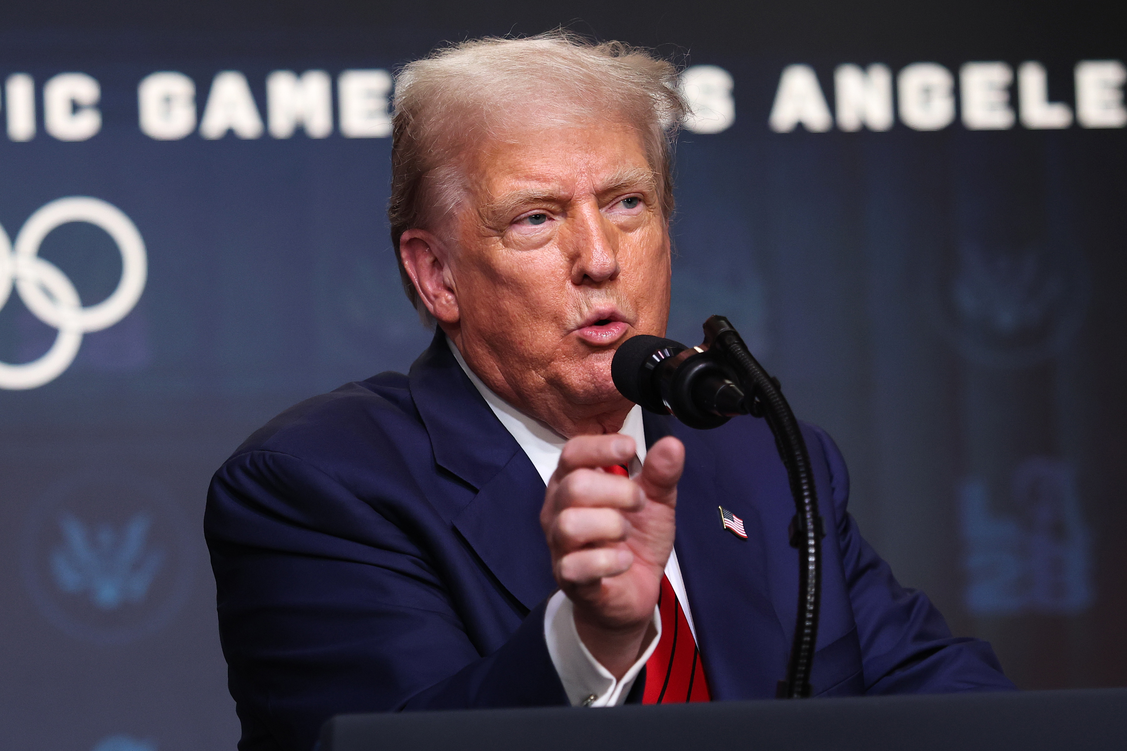 Hablando por el micrófono, Donald Trump se dirige a la prensa tras firmar una orden ejecutiva en el Auditorio South Court, en la que esboza planes para respaldar los Juegos Olímpicos de Los Ángeles de 2028.