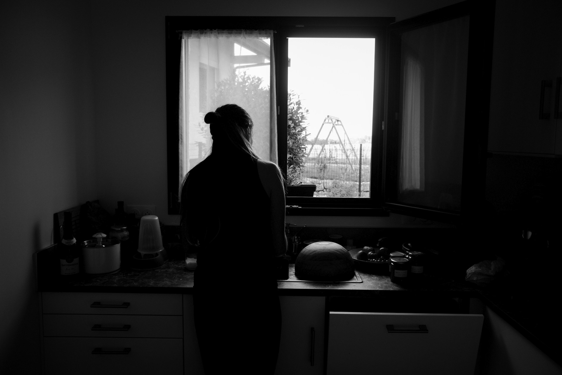 Toma en escala de grises de una mujer de pie en la cocina | Fuente: Unsplash