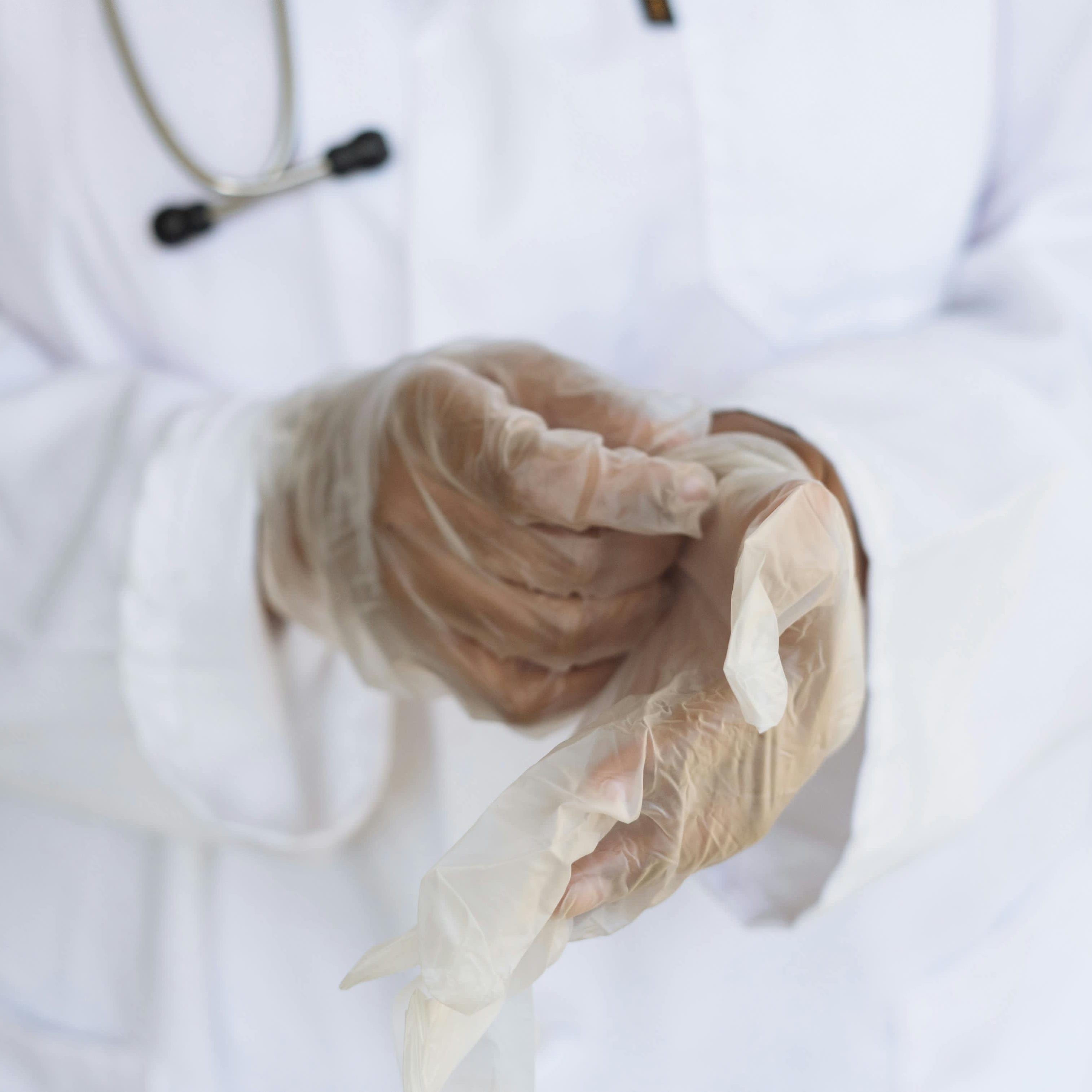 Un profesional médico tirando de guantes de látex | Fuente: Pexels