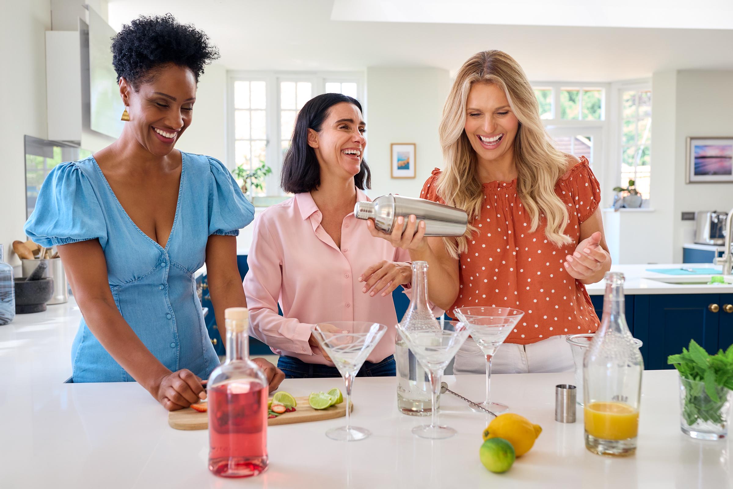 Tres amigas divirtiéndose mezclando cócteles | Fuente: Getty Images