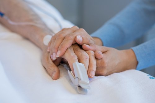 Enfermera toma la mano de una paciente de la tercera edad. | Foto: Shutterstock